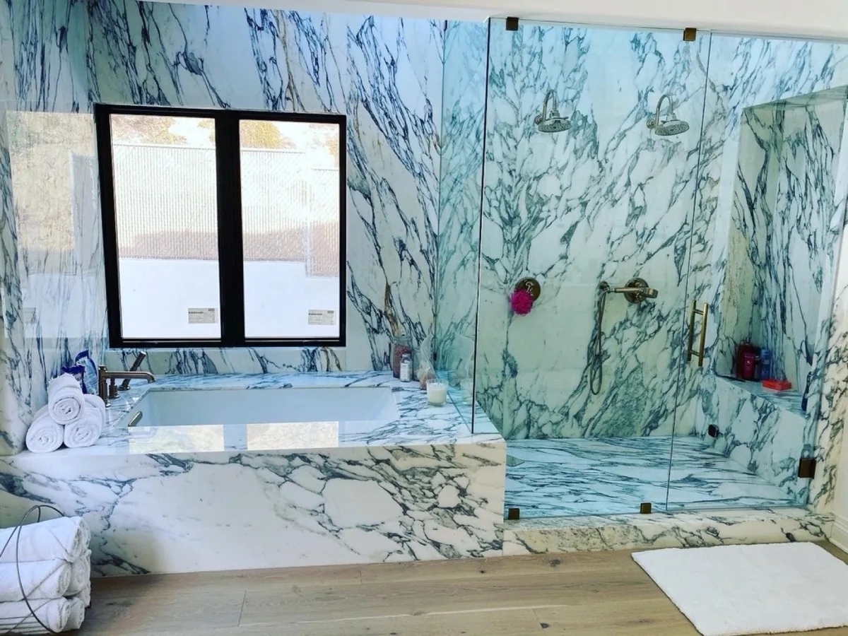 Marble primary bathroom with a backlit LED mirror and glass shower