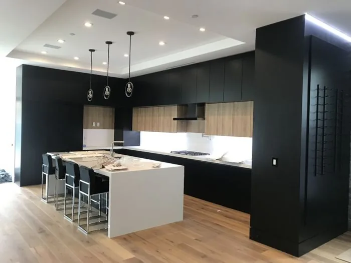 Custom black cabinetry kitchen with a waterfall-edge island and walnut cabinetry