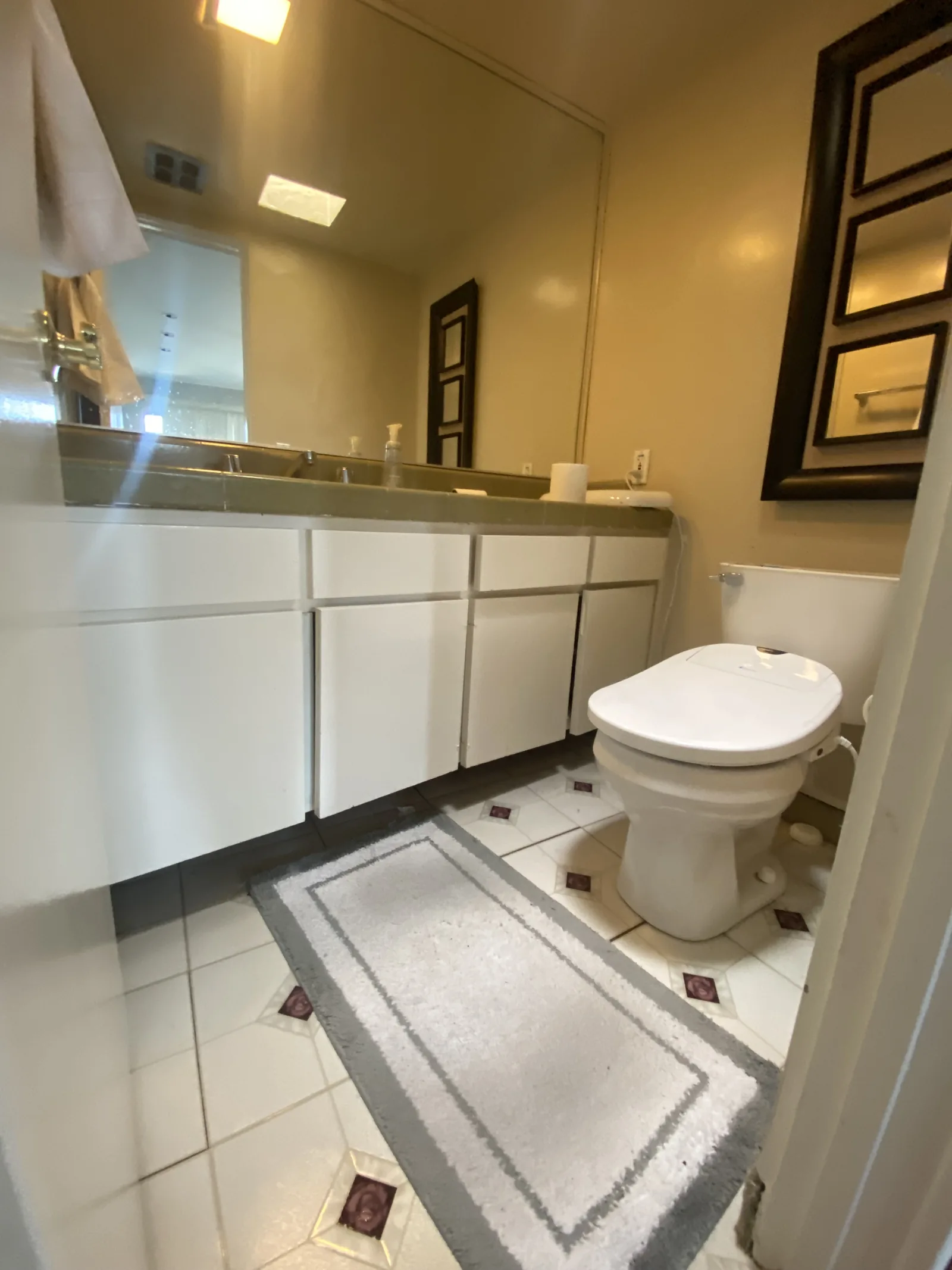 The original bathroom with a floor-mounted toilet and a decorative diamond-pattern tile floor