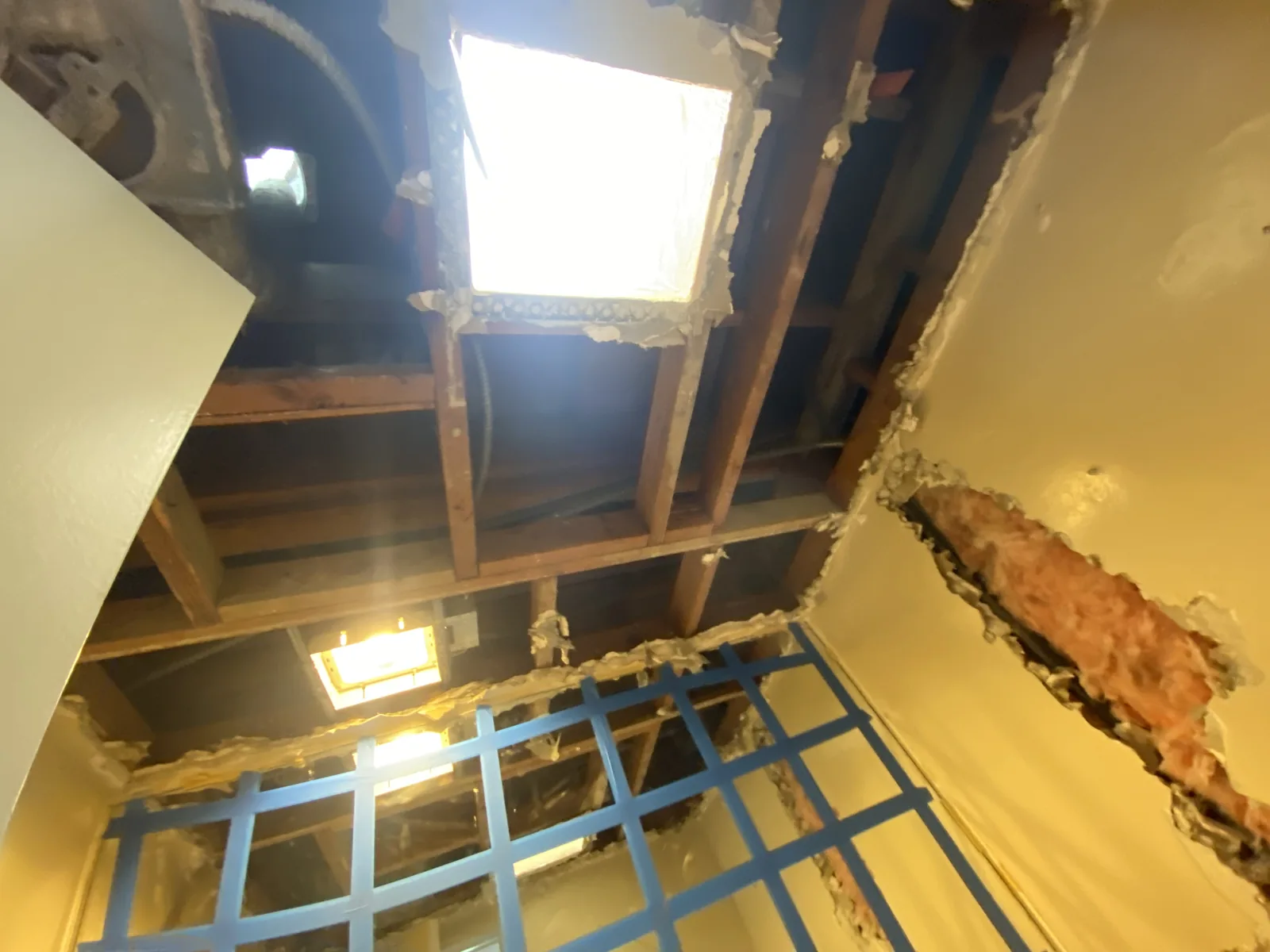 The old skylight removed, leaving an open ceiling well with a work light lowered through it