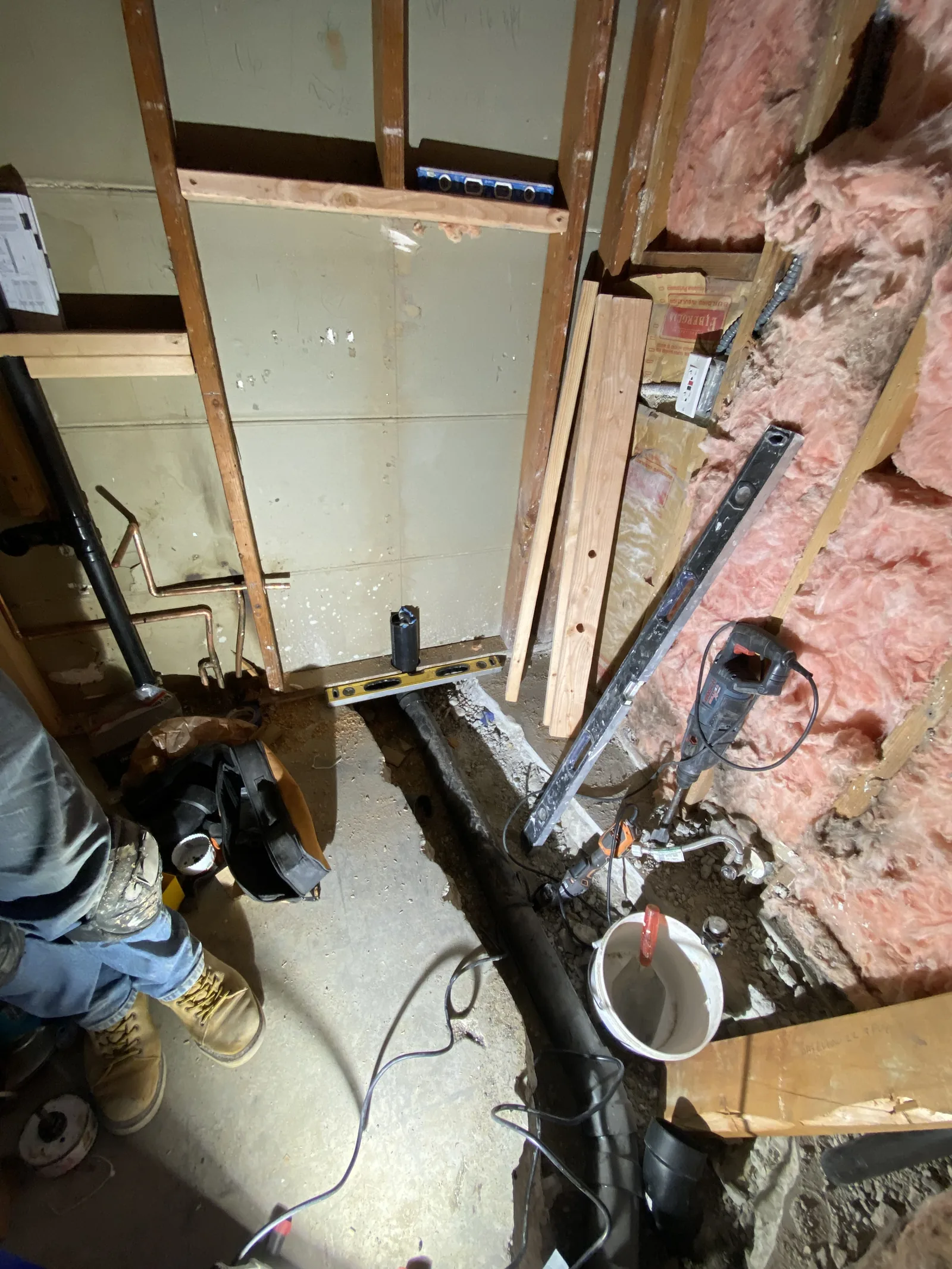 A cut trench in the concrete slab with a level laid across the waste pipe to check its grade