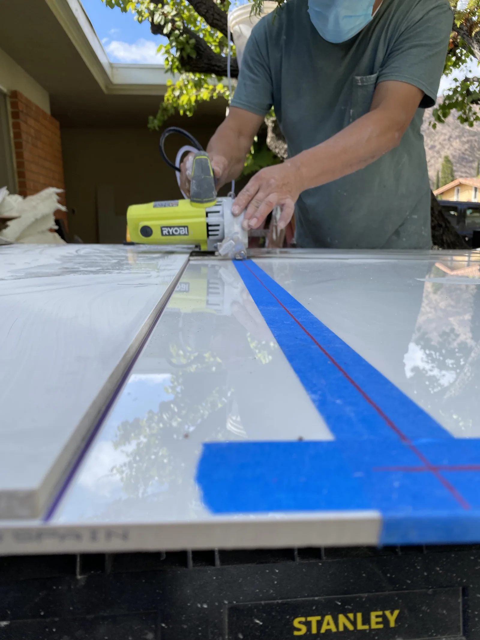 A close view of a tile saw blade cutting along a marked guideline on a large tile
