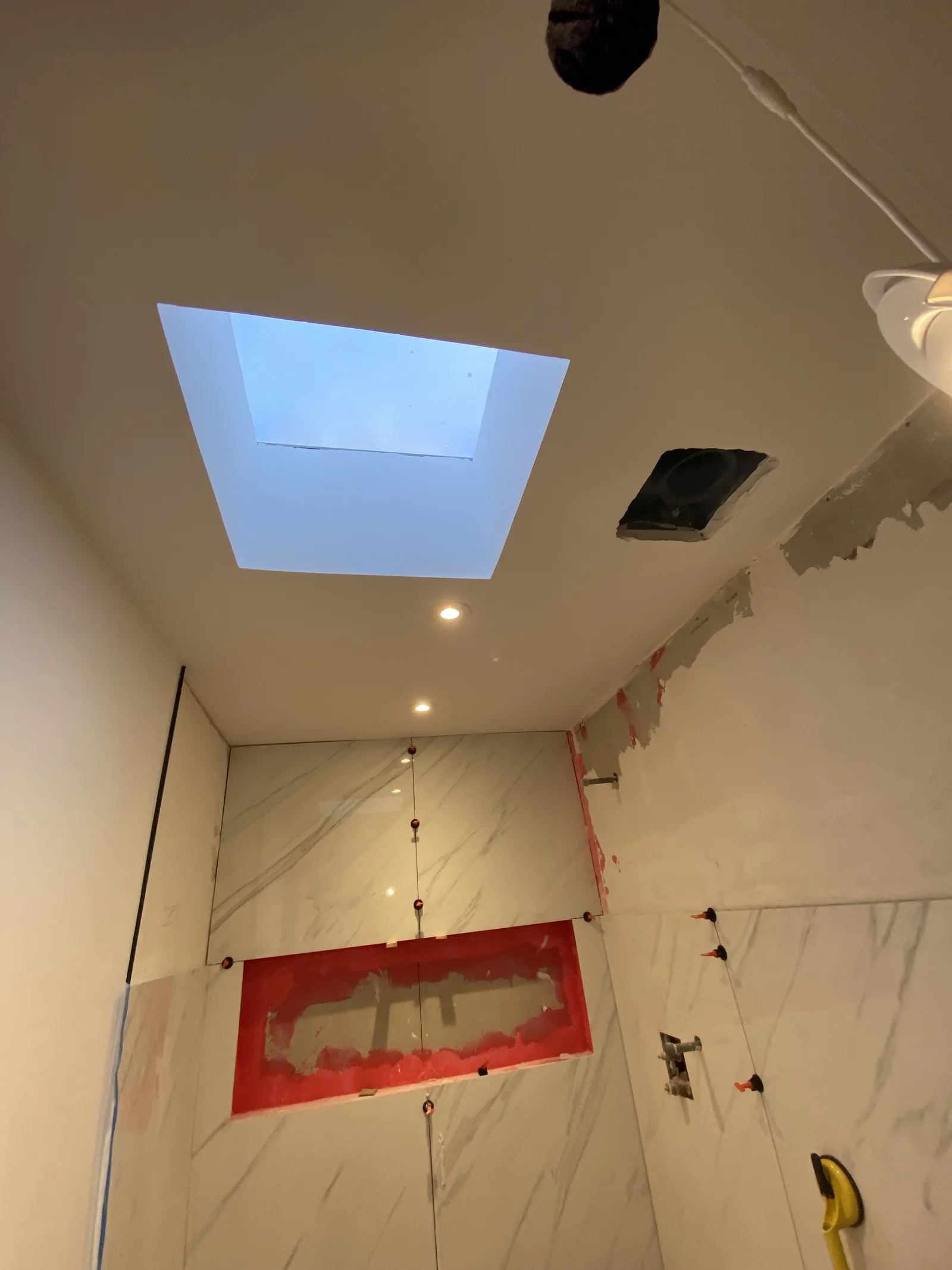 The new skylight seen from below, with large-format tile installed on the wall underneath it