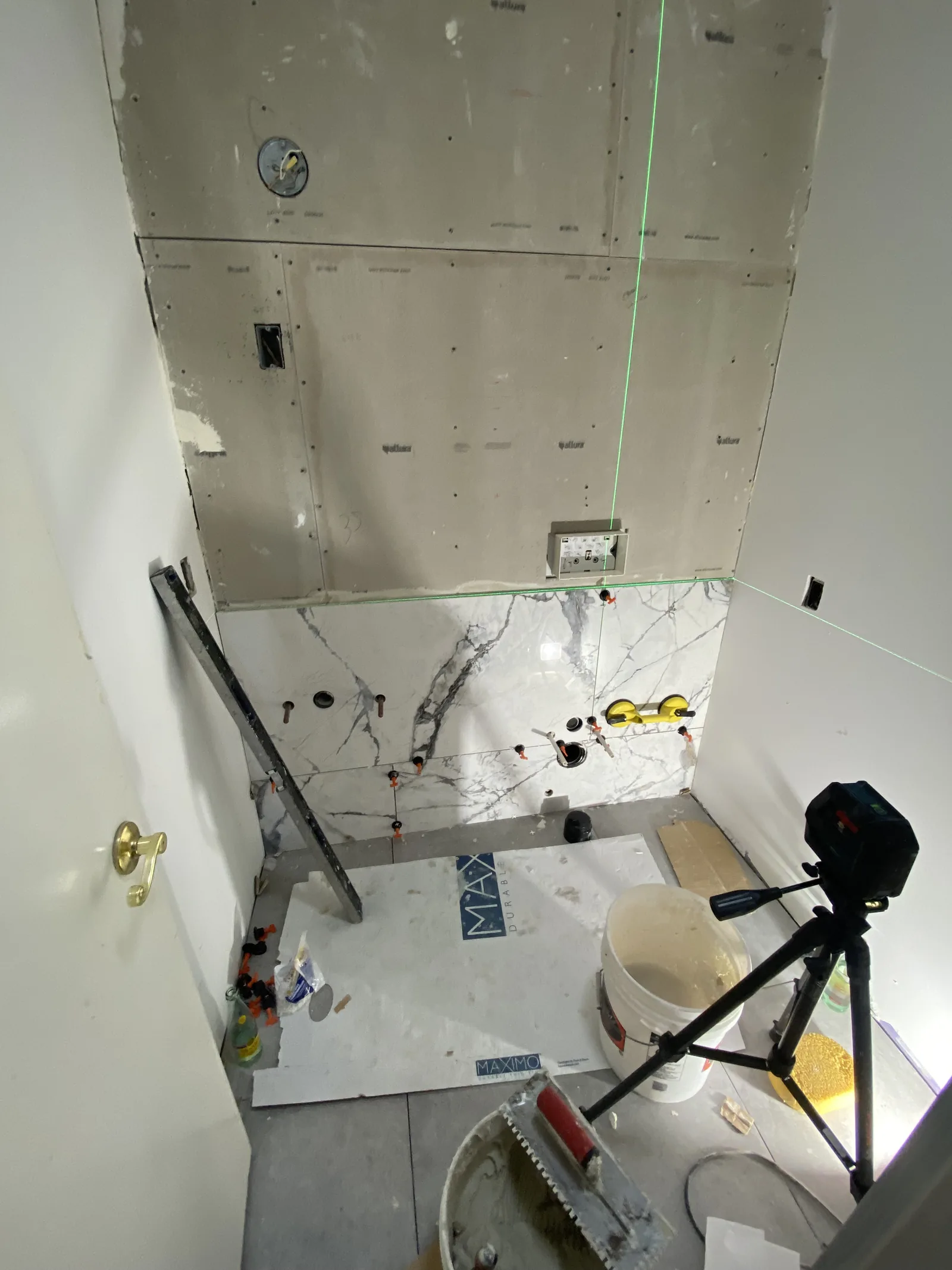 A small powder room with tile progressing from floor to ceiling, guided by a laser level