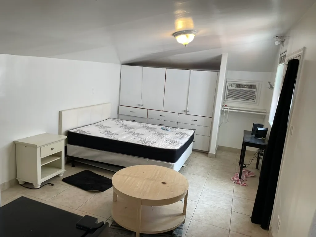 The original bedroom wall of white built-in cabinets, with a wall air conditioner to the right