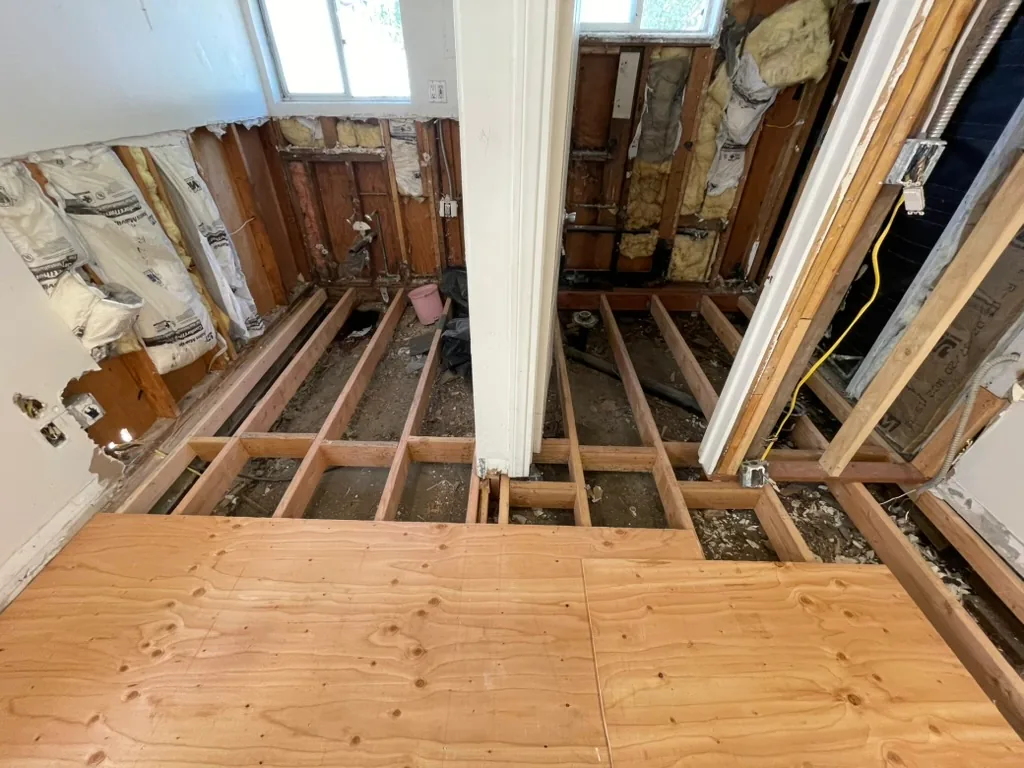 New plywood subfloor laid over new joists at the kitchen and bathroom end of the unit