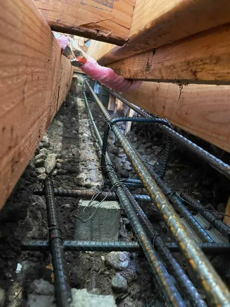 Rebar tied in a trench beneath the floor framing before the concrete pour