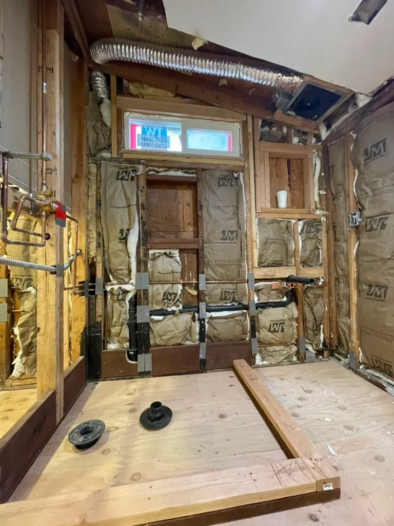 The bathroom reframed and insulated, with a new window, drain fittings and a framed shower curb