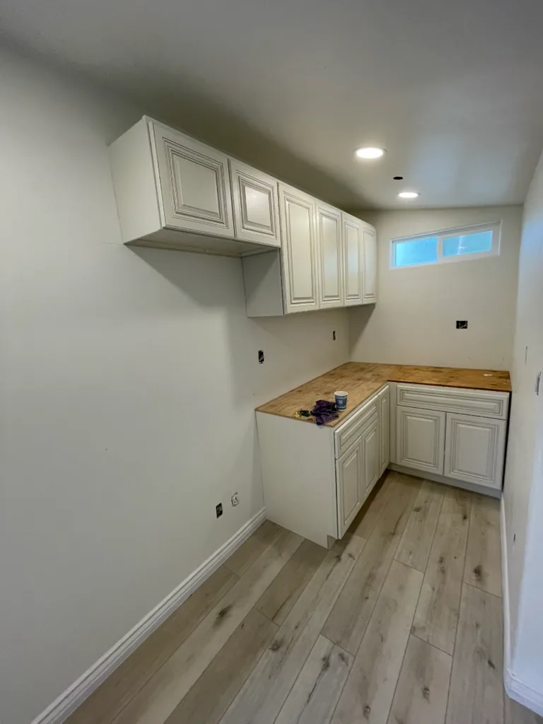 New cream kitchen cabinets installed on new wood-look flooring, before the countertops