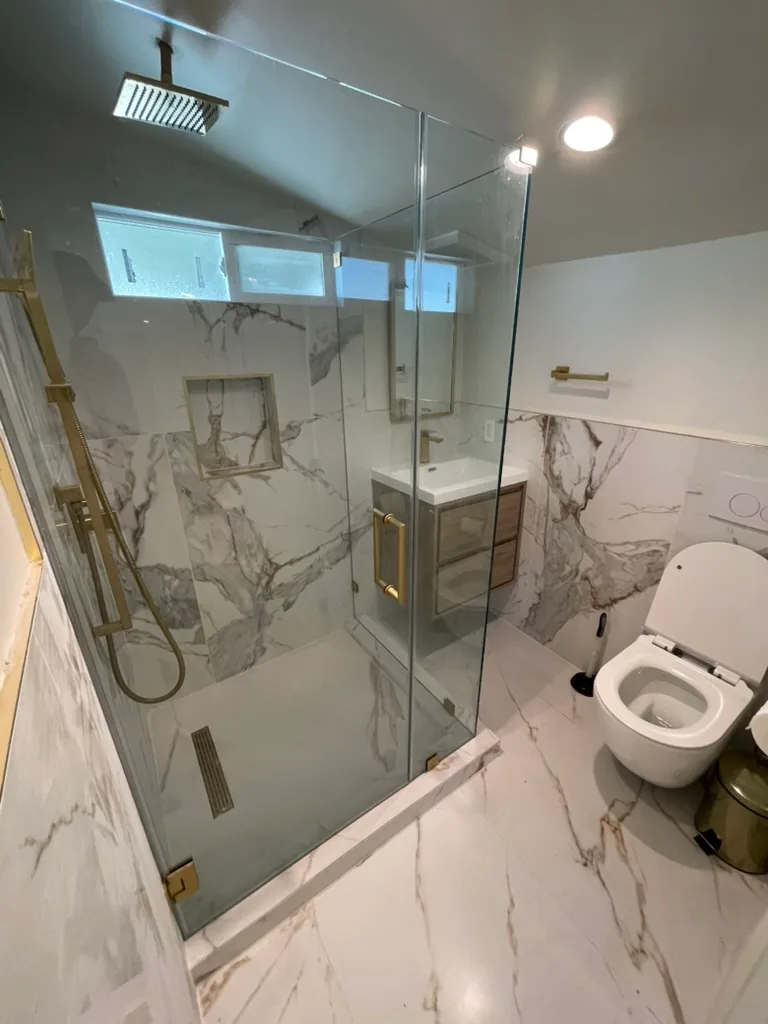 The finished bathroom with a frameless glass shower, a wall-hung vanity and a wall-mounted toilet
