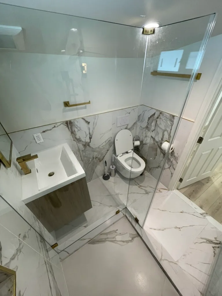 A wall-mounted toilet and wall-hung vanity, with large veined tile on the floor and lower walls