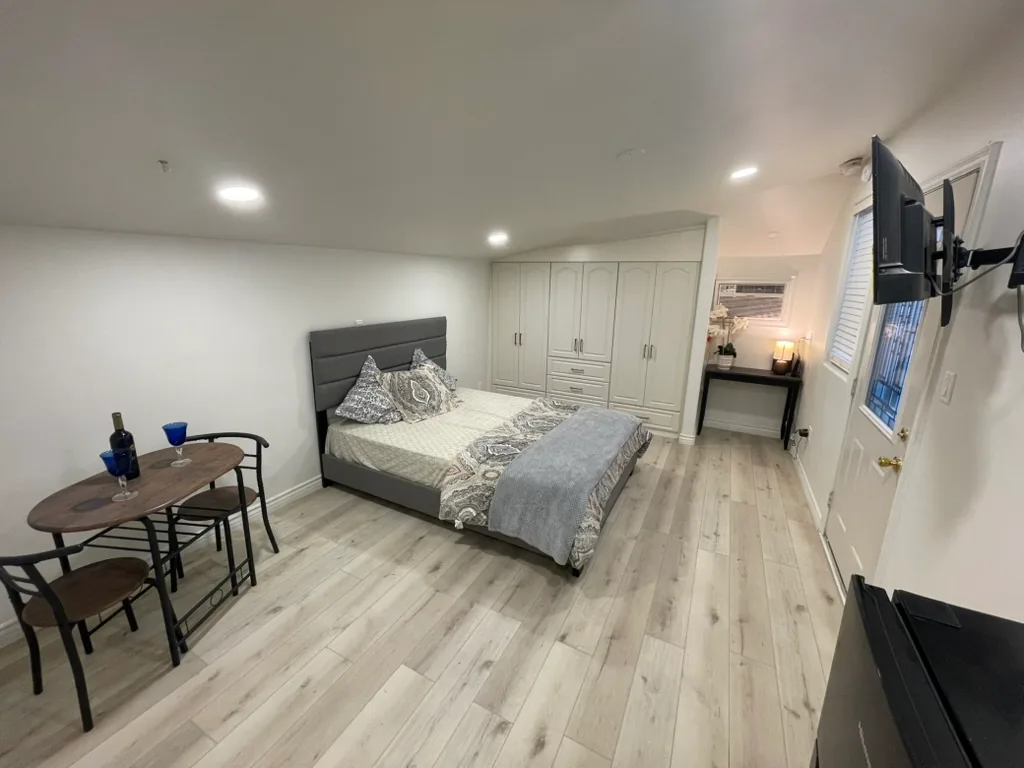 The finished bedroom with new built-in closets, a wall air conditioner above a desk and new flooring