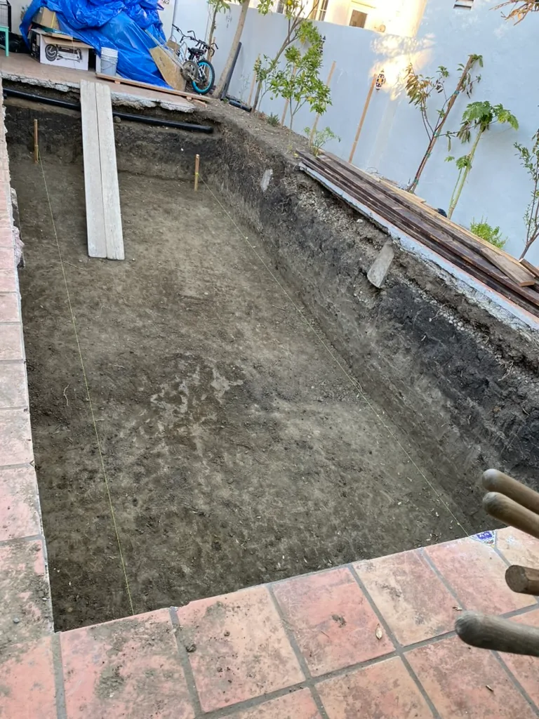 A rectangular excavation cut into a terracotta patio