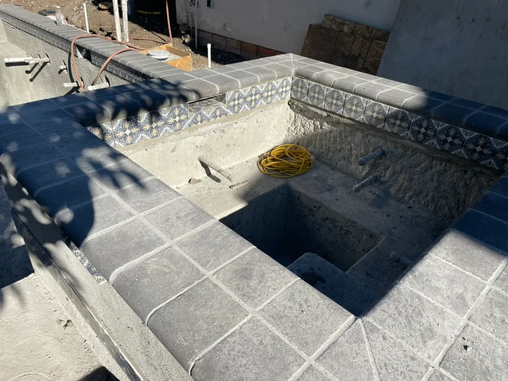 Grey coping and patterned blue waterline tile set around the spa