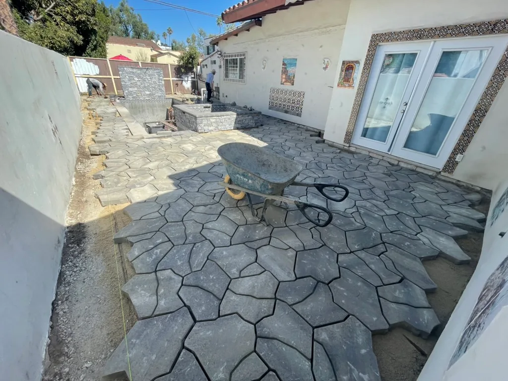 Large grey pavers going down on the patio, with a wheelbarrow on them