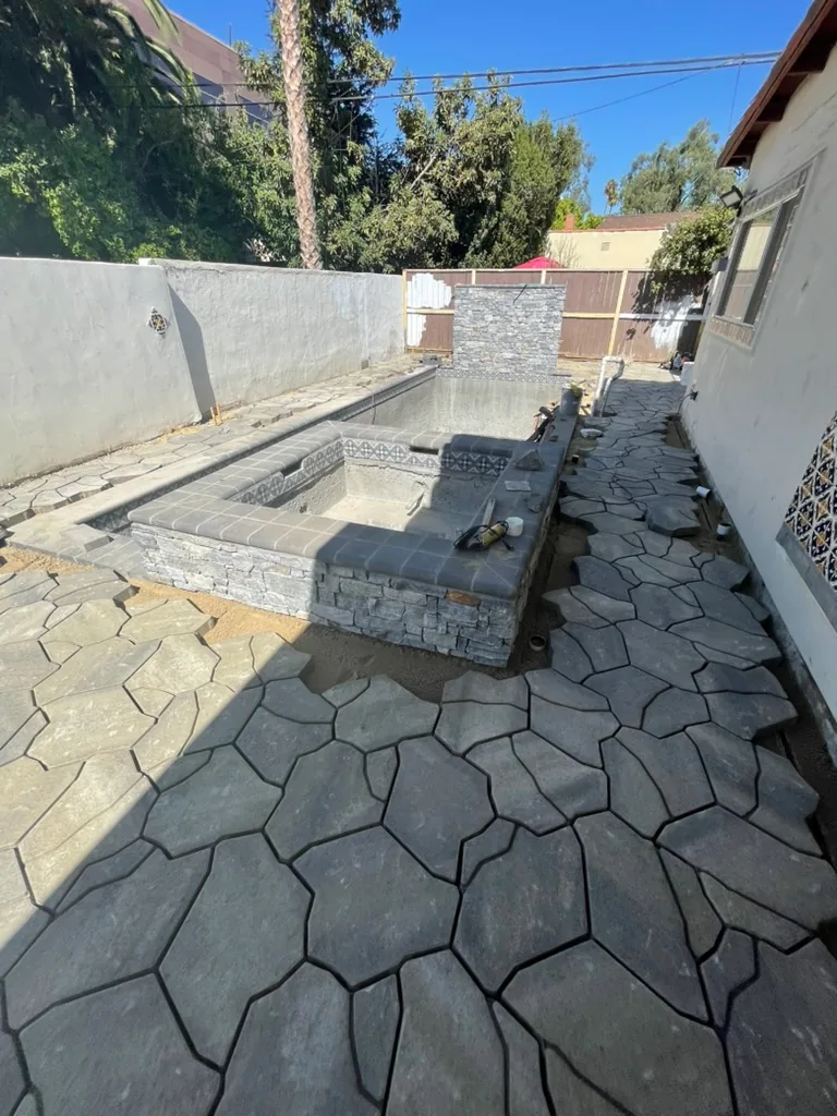 Grey pavers laid up to the stone-faced spa