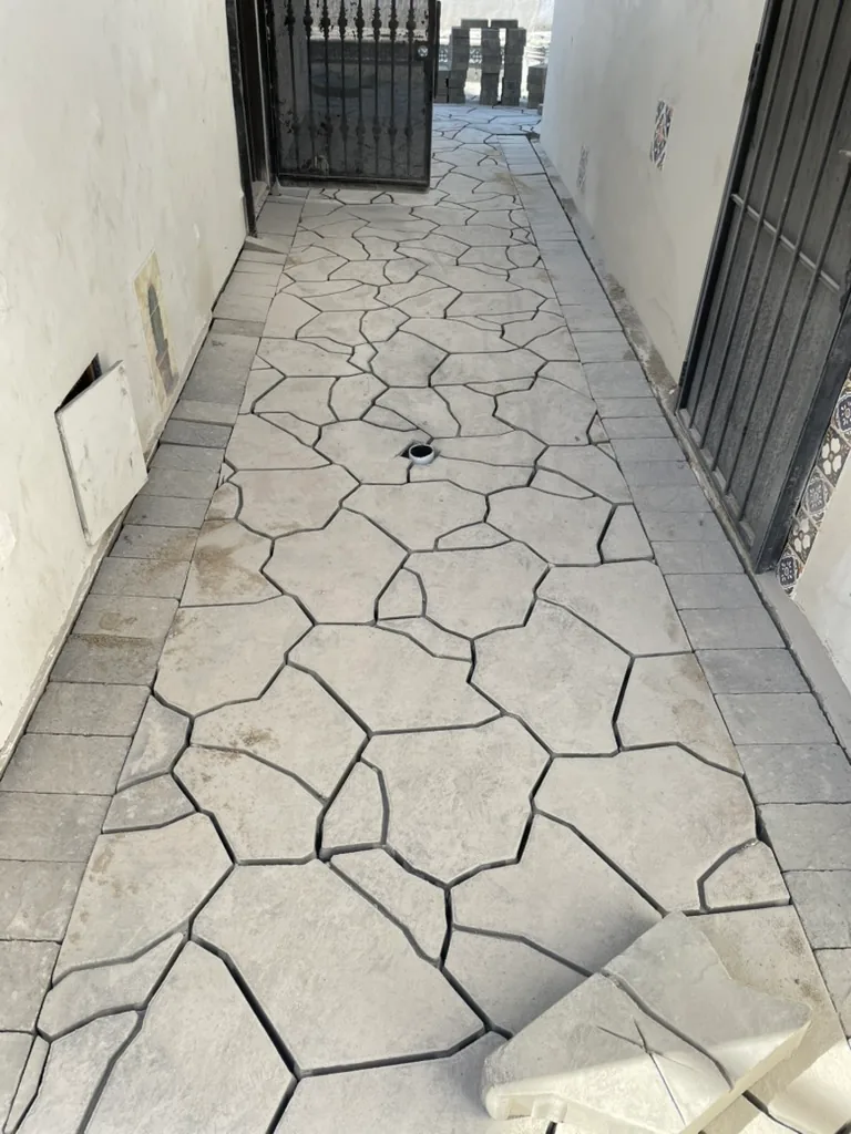 A narrow side passage finished in grey pavers, ending at an iron gate