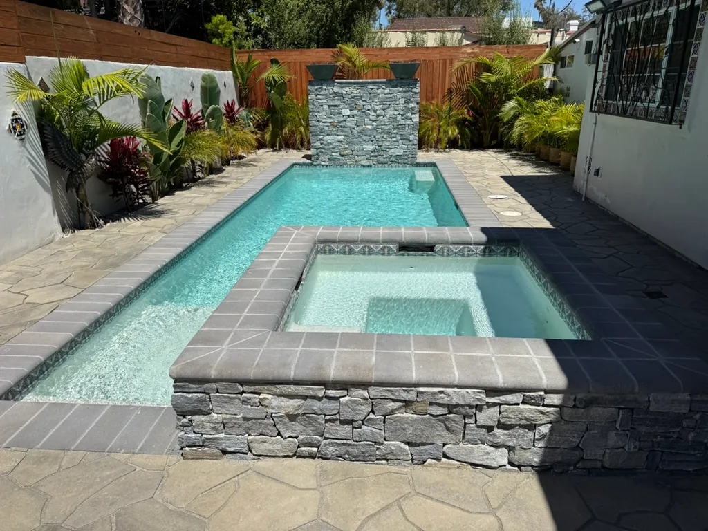 The finished pool and stone spa with tropical planting grown in along the walls