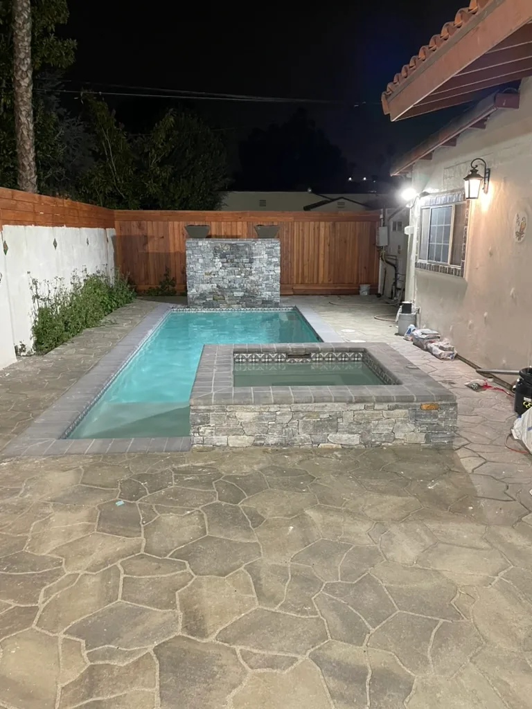 The finished yard at night, lit by lanterns on the house wall