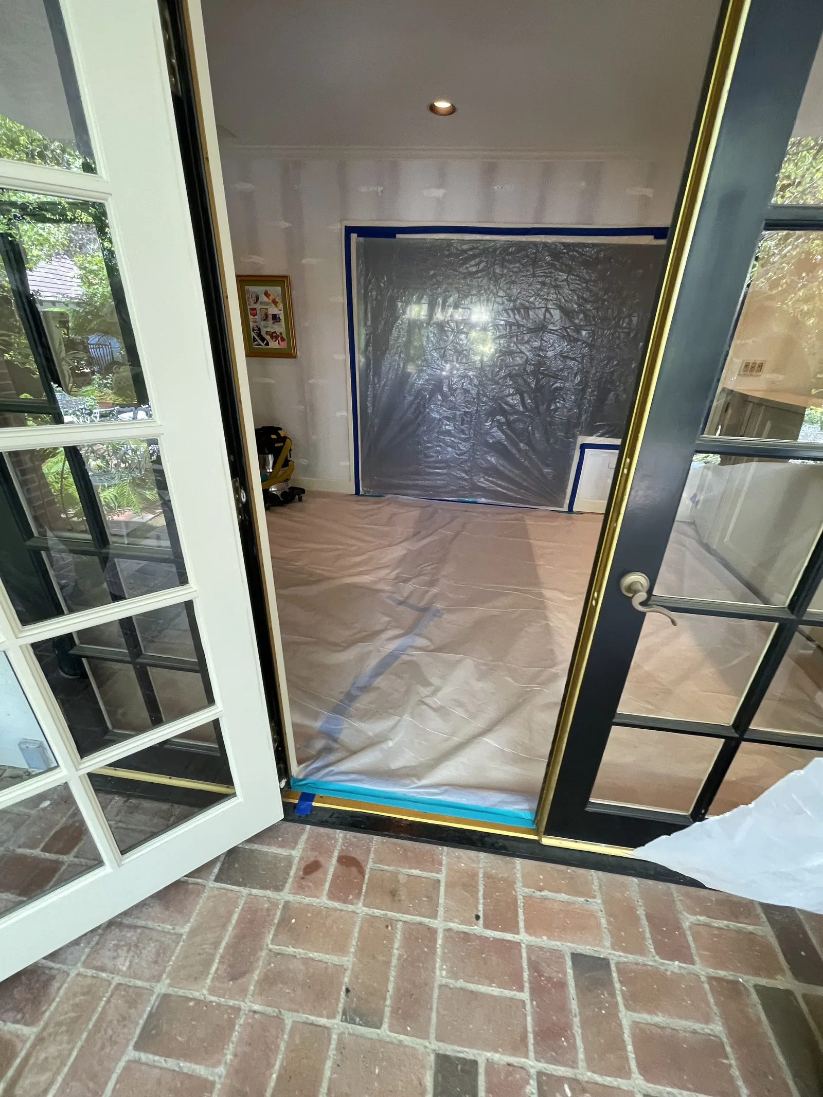 French doors open to a room with plastic containment visible inside