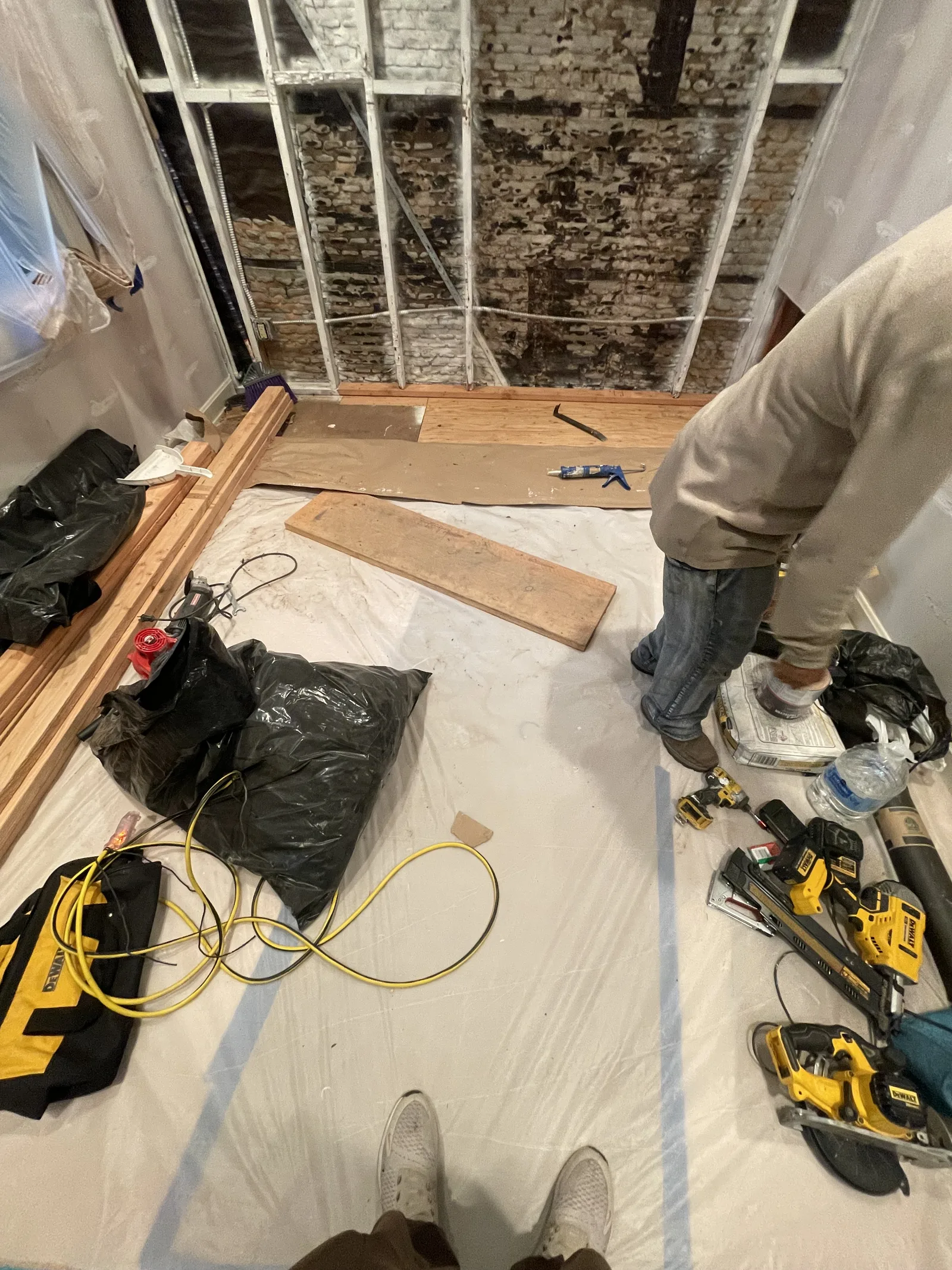 A worker applying a red waterproofing membrane to new wall sheathing
