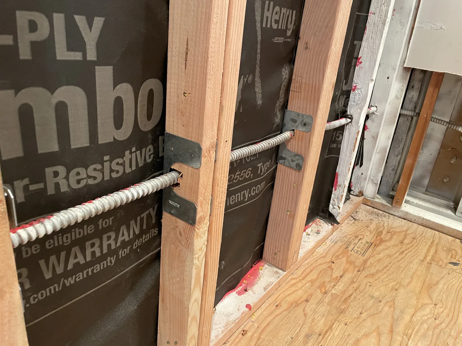 A close view of new framing with a weather-resistive barrier and metal connectors