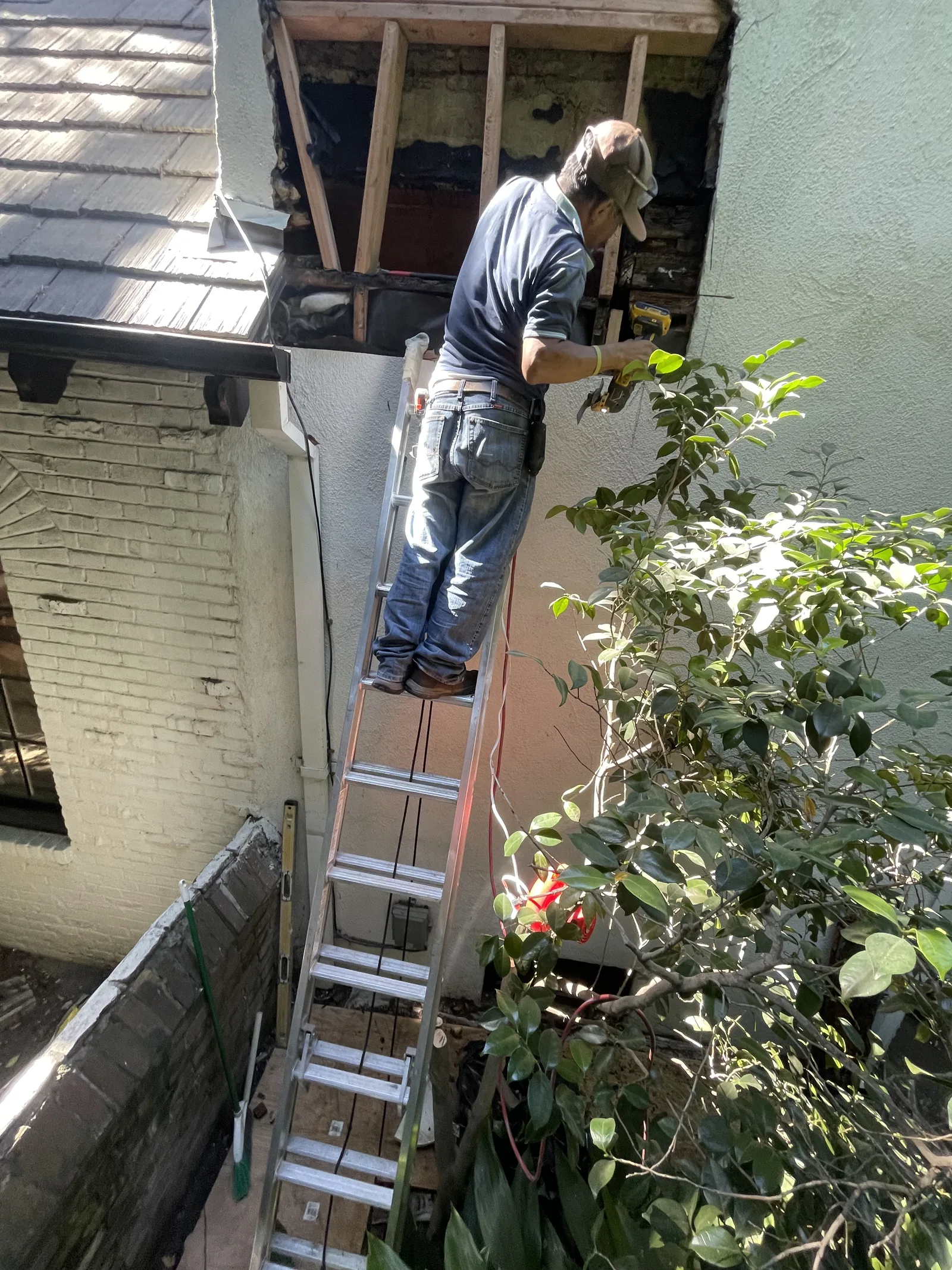 A worker on a ladder at the exterior wall below a second-floor window