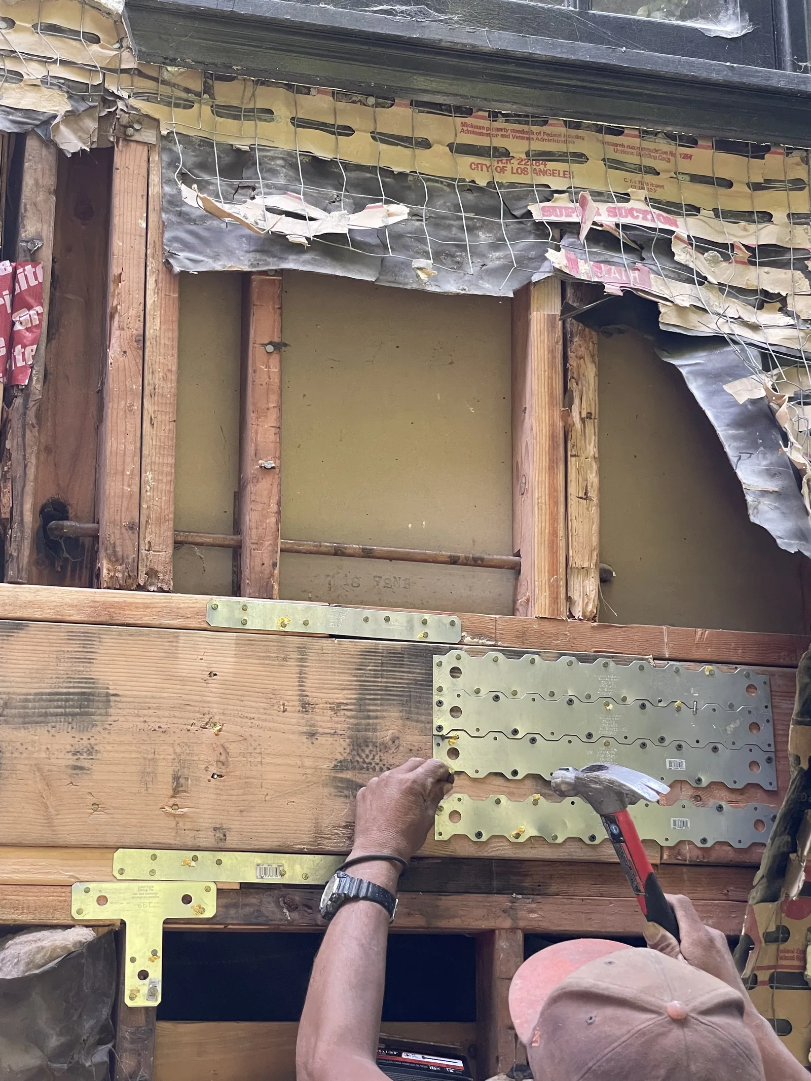 A worker securing metal connector plates to new framing