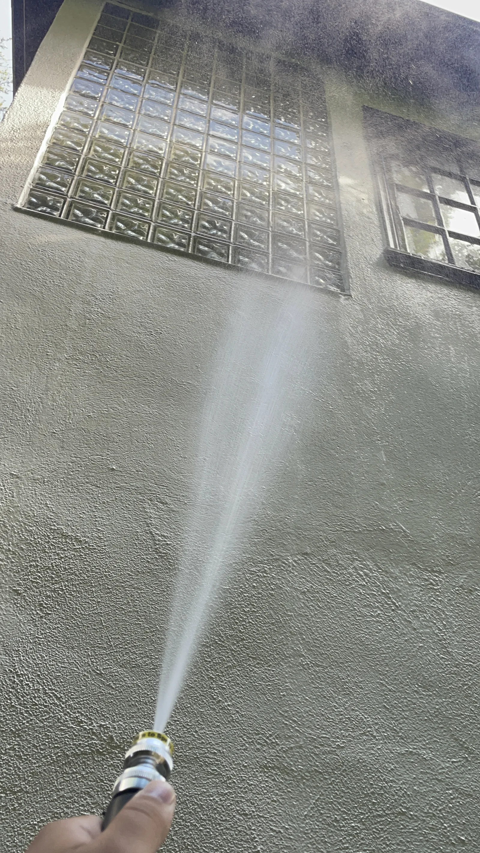 Water sprayed against a repaired exterior wall below a window