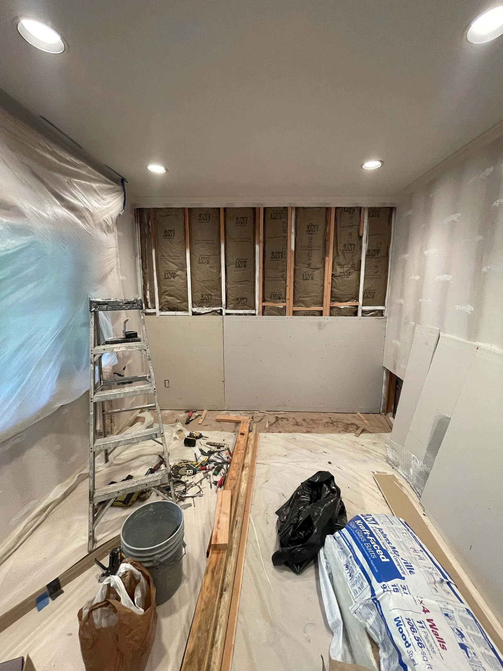 Drywall installed on the lower section of an interior wall, framing exposed above