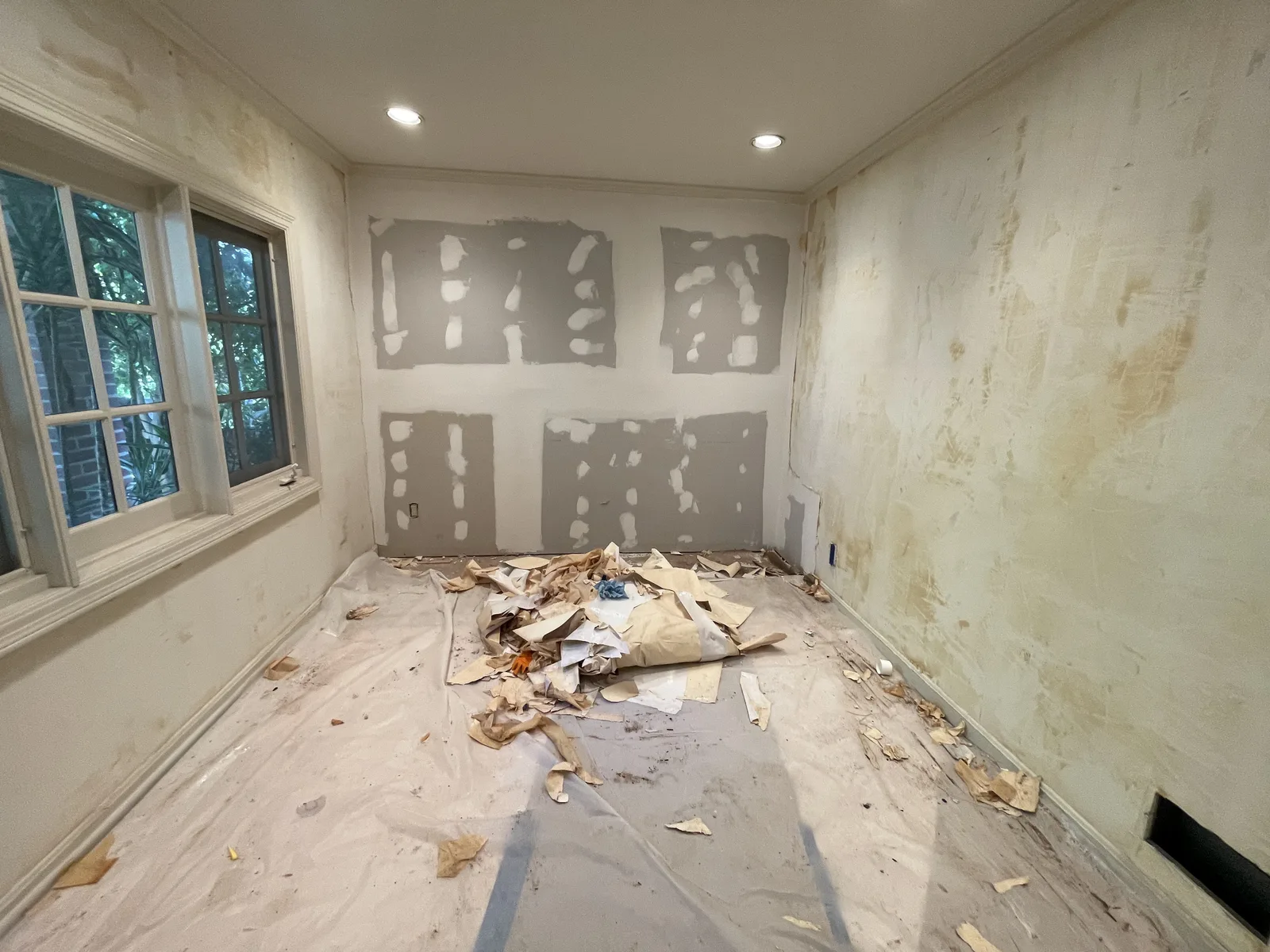 Wallpaper removal in progress, with adhesive residue left on the walls