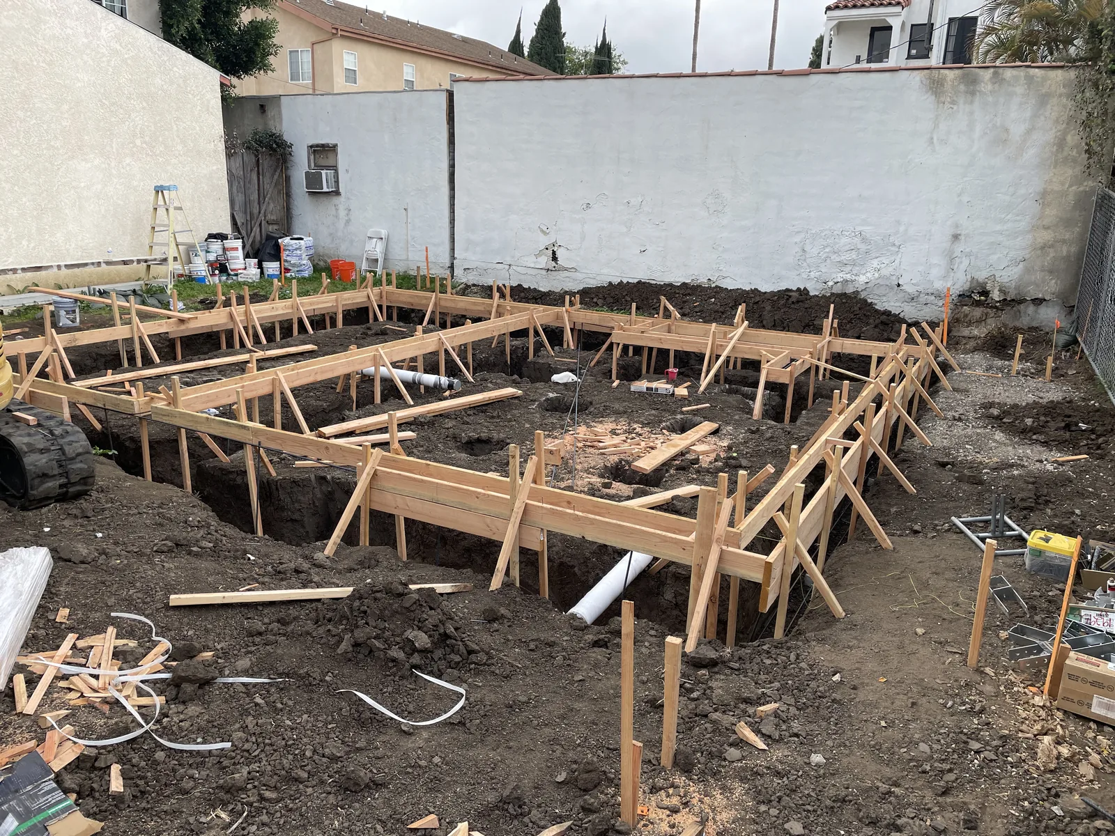 An excavated foundation trench with wood forms staked out where the garage used to stand