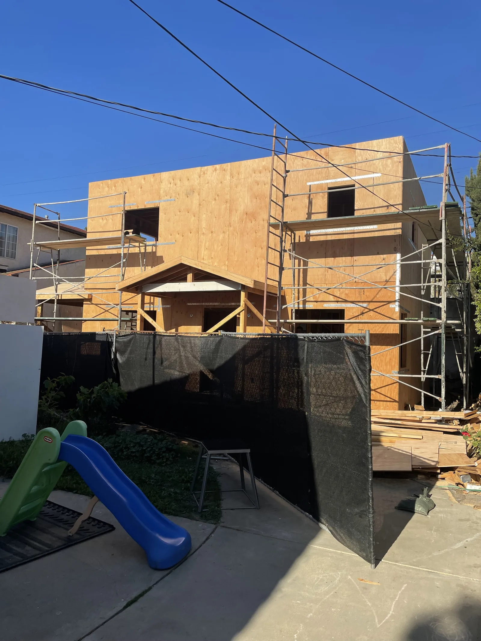 A two-story structure under construction, sheathed and scaffolded, on a Beverlywood lot