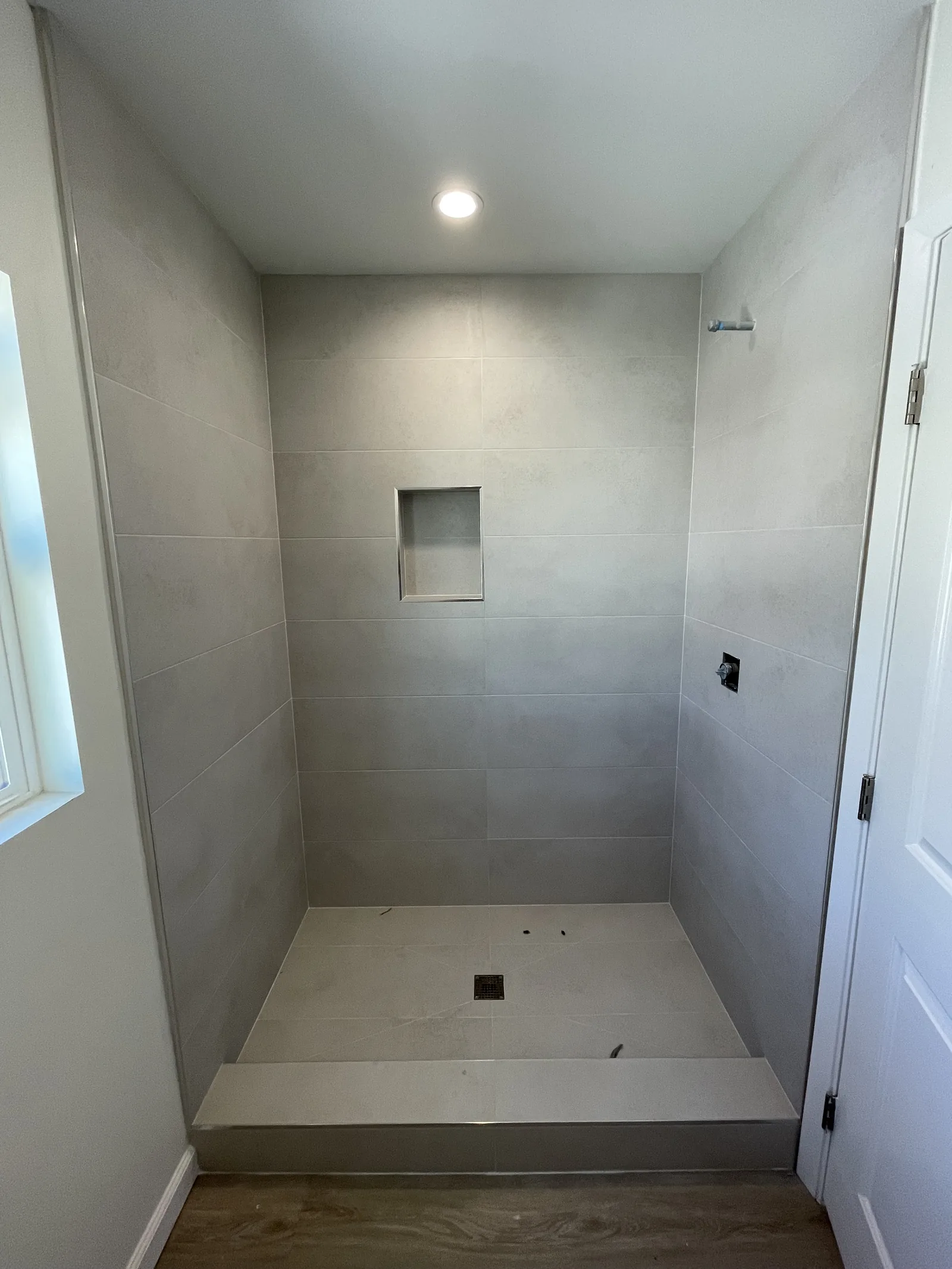 A tiled shower stall ready for its glass door