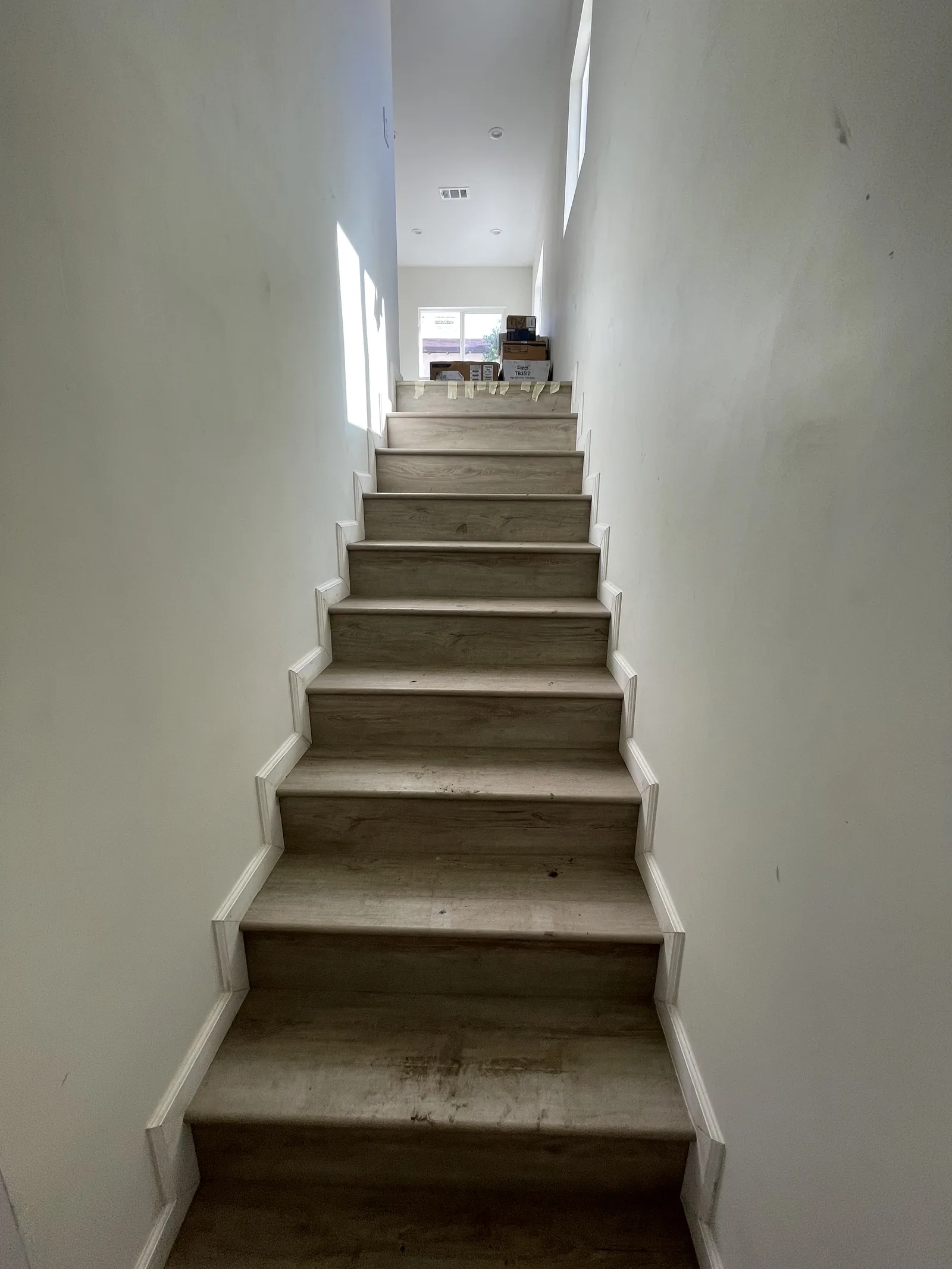 A near-finished staircase with vinyl plank treads and painted walls