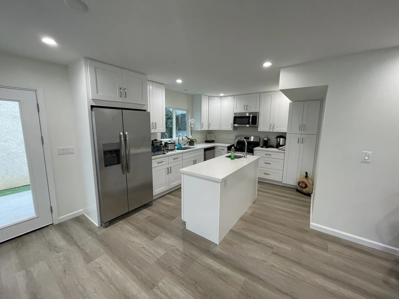 The finished kitchen of a new two-story ADU, with white shaker cabinets and an island