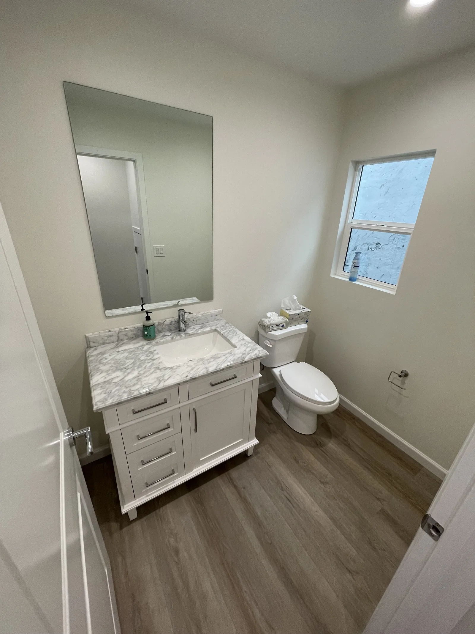 The ADU's finished guest powder room with a white vanity and marble-look countertop
