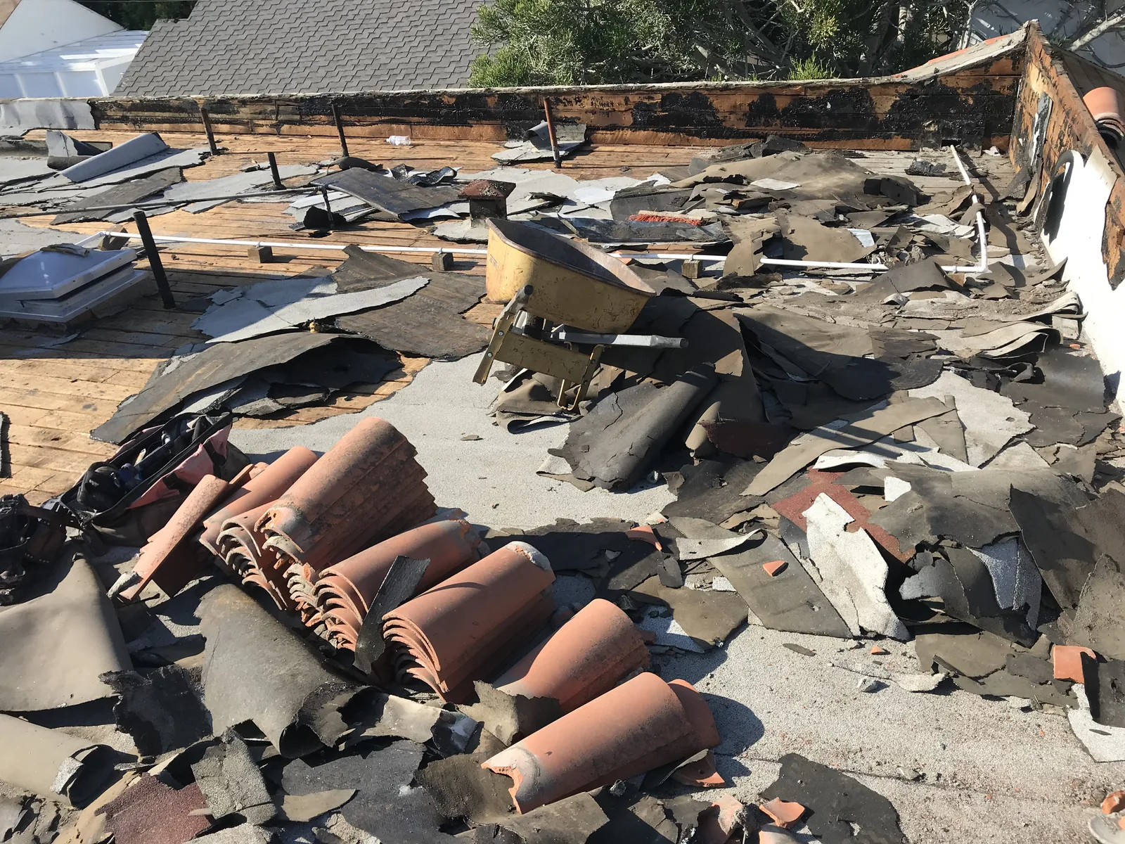 The old tile roof torn off, with the parapet wall exposed down to the decking