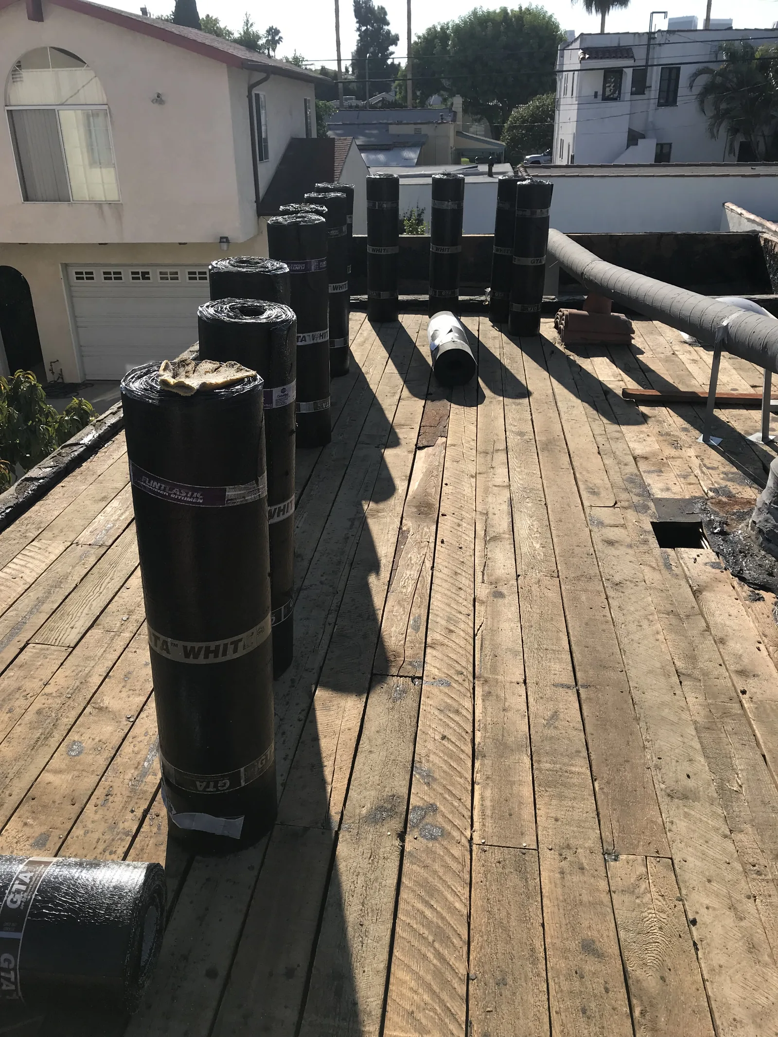 Rolls of new roofing membrane staged on the bare roof deck
