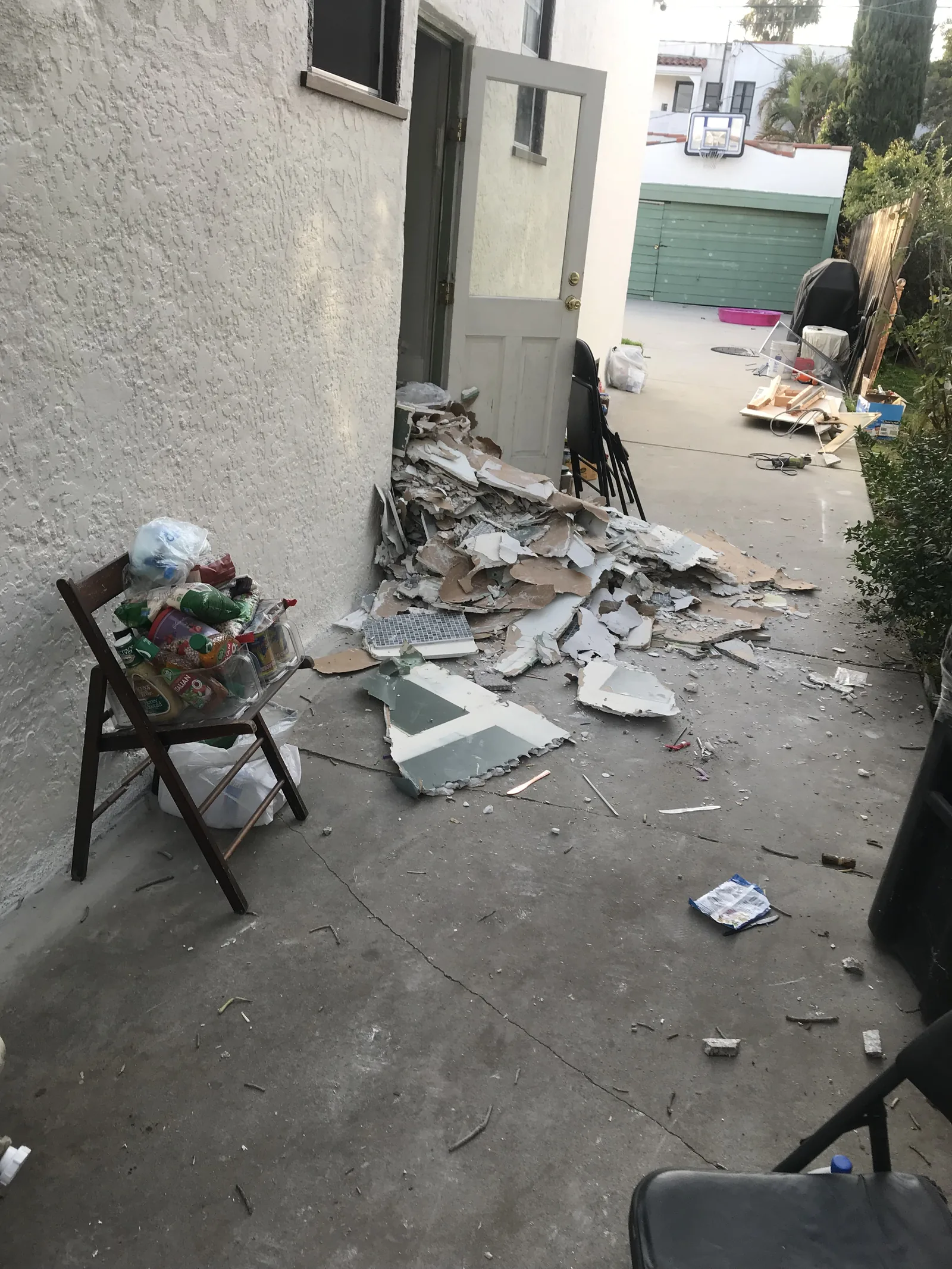 A pile of drywall and tile demolition debris in the side yard