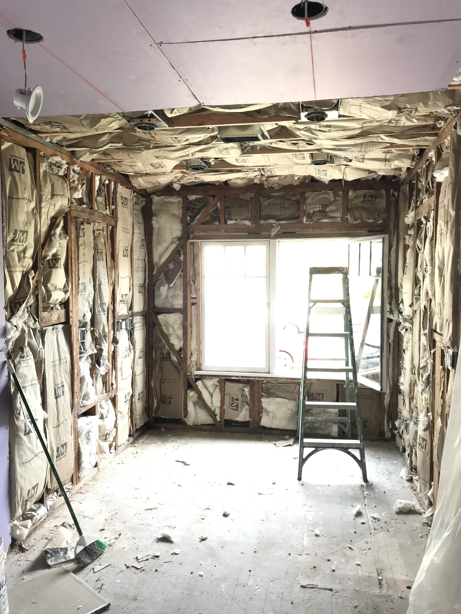 Fresh fiberglass insulation batts filling the kitchen wall framing