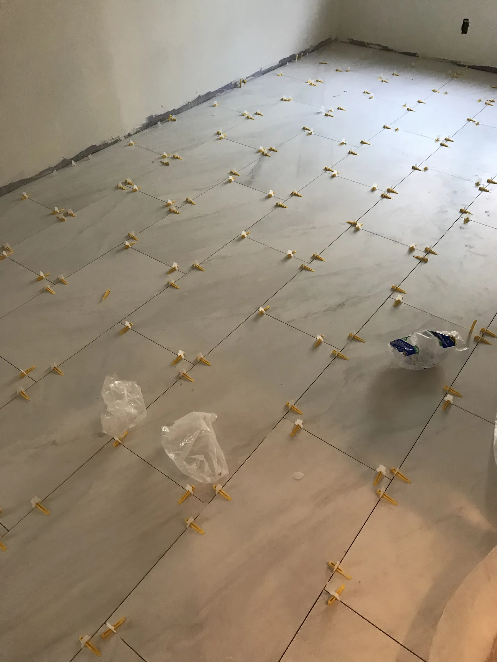 New floor tile being installed with leveling clips at the seams