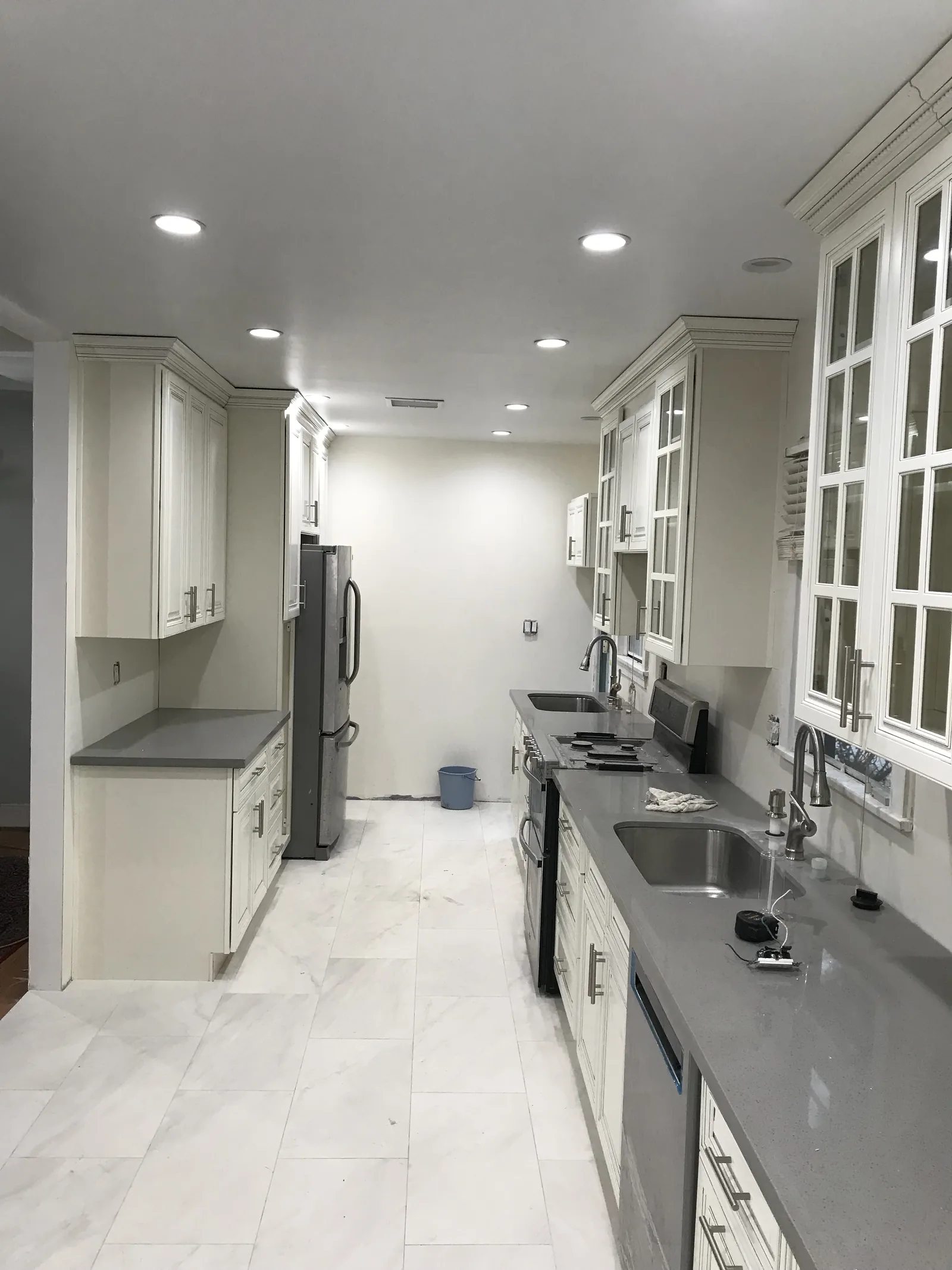 The finished kitchen with white cabinetry, quartz counters, and new windows