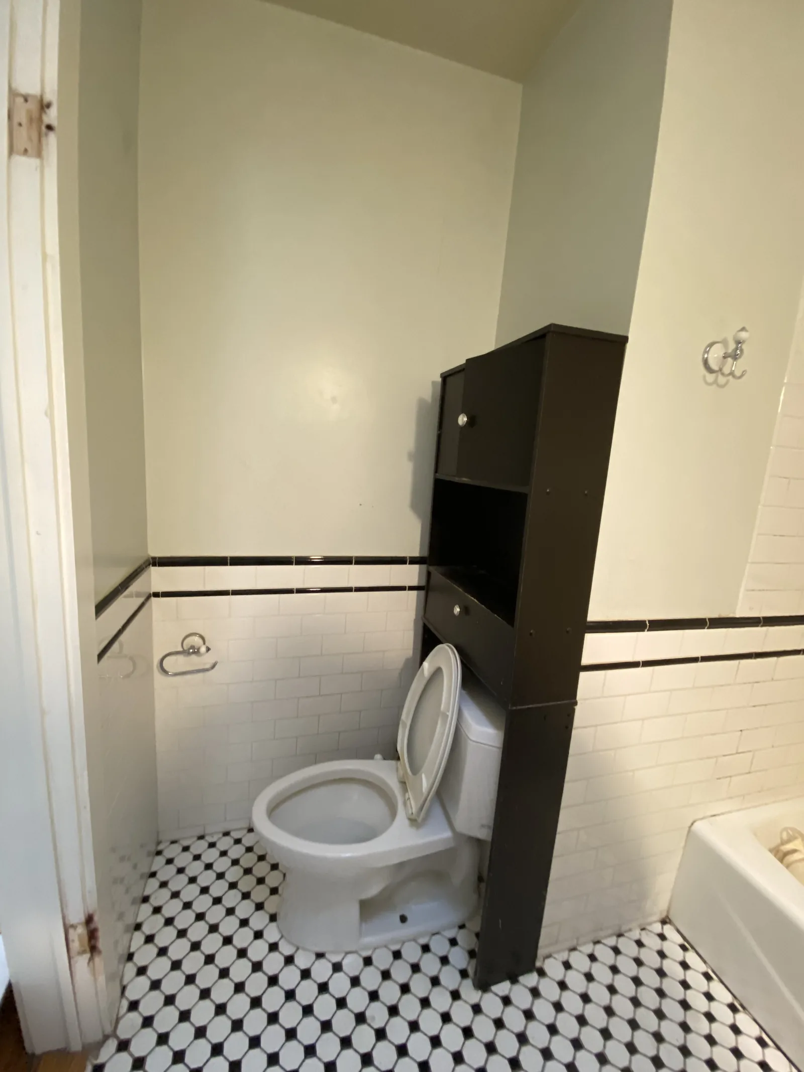 The original toilet niche with its dated tile and a dark wood cabinet