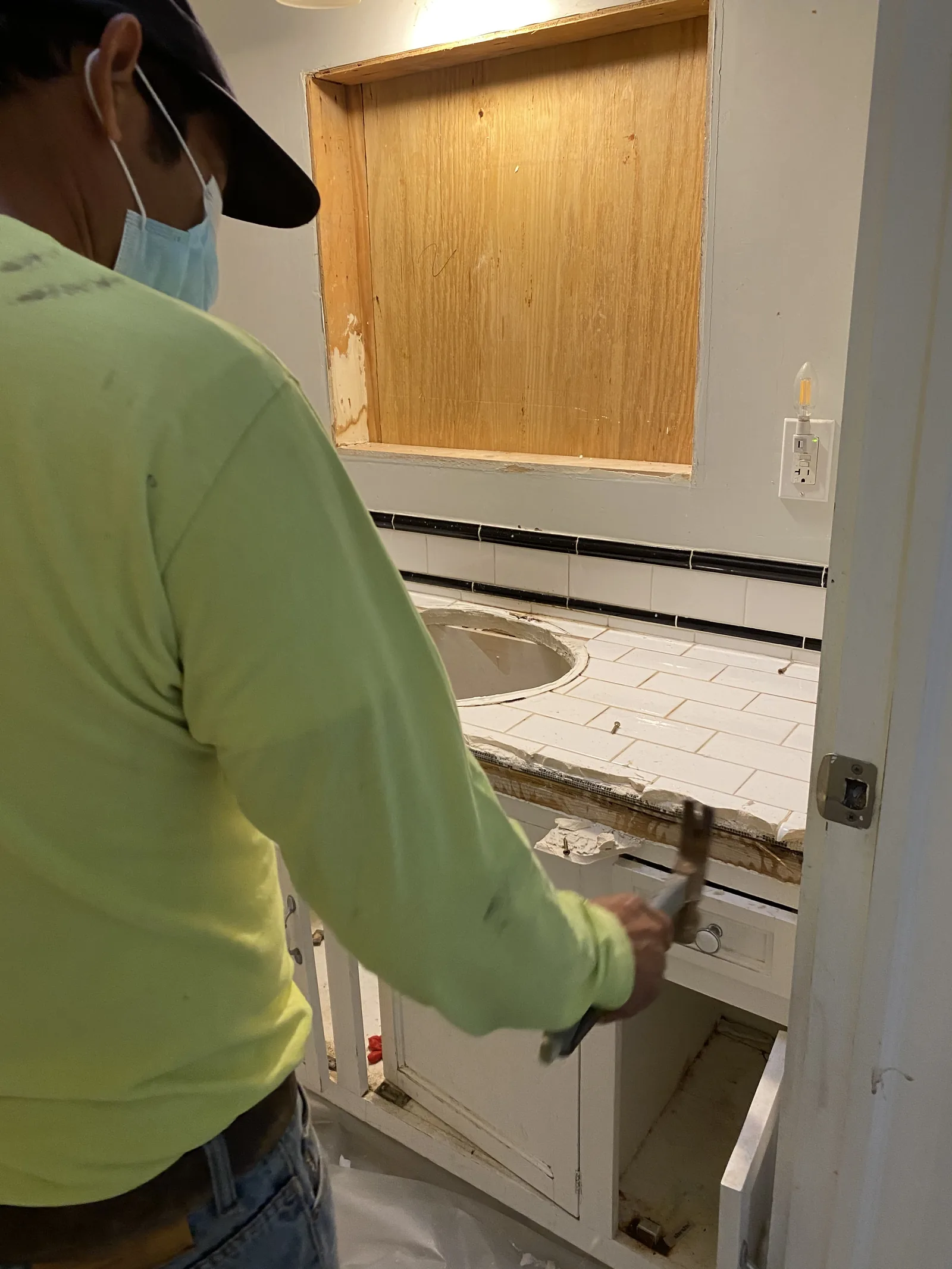 A worker prying up the original tile countertop during demolition