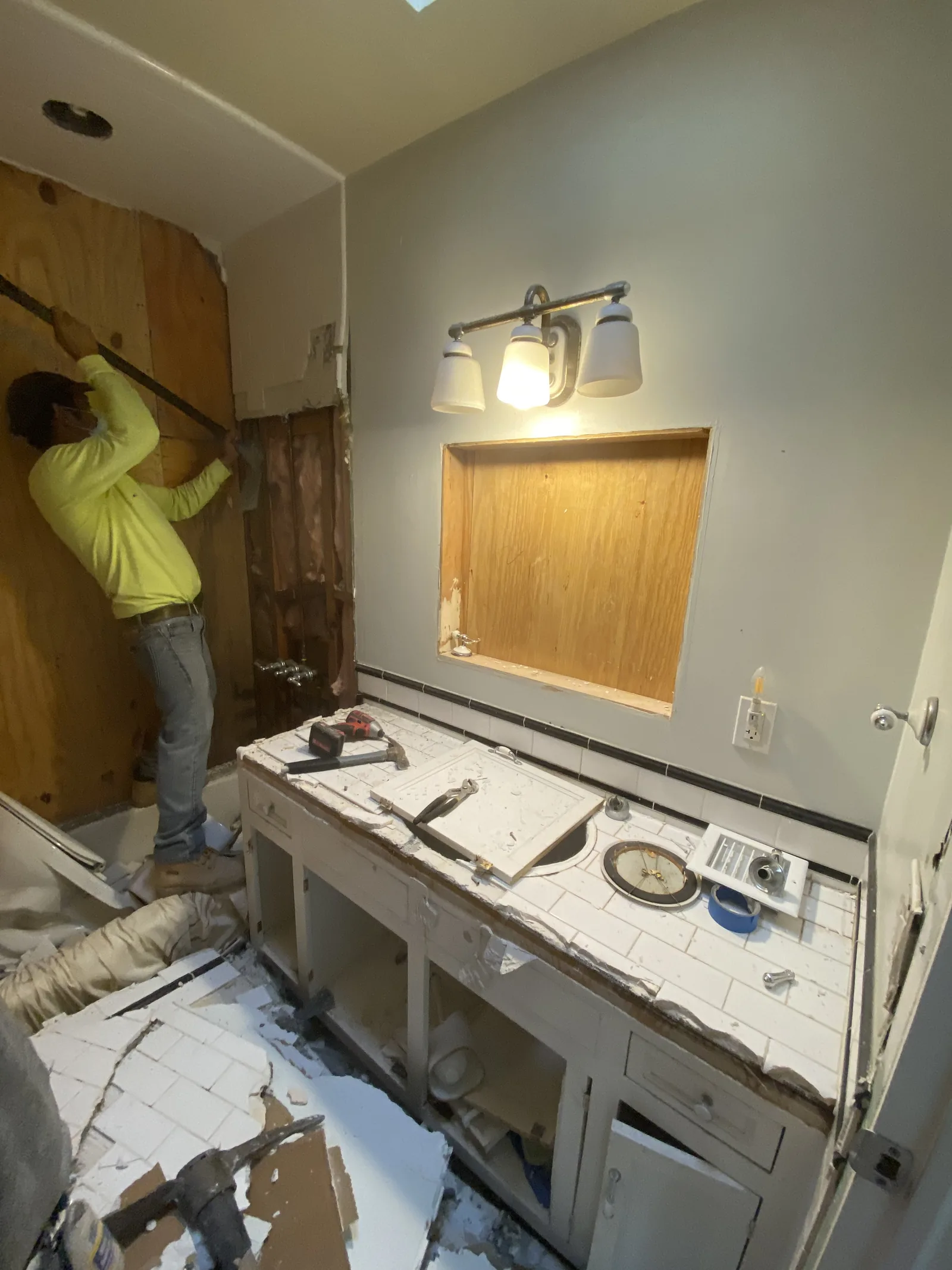 A worker removing the old tile surround from a tub during demolition