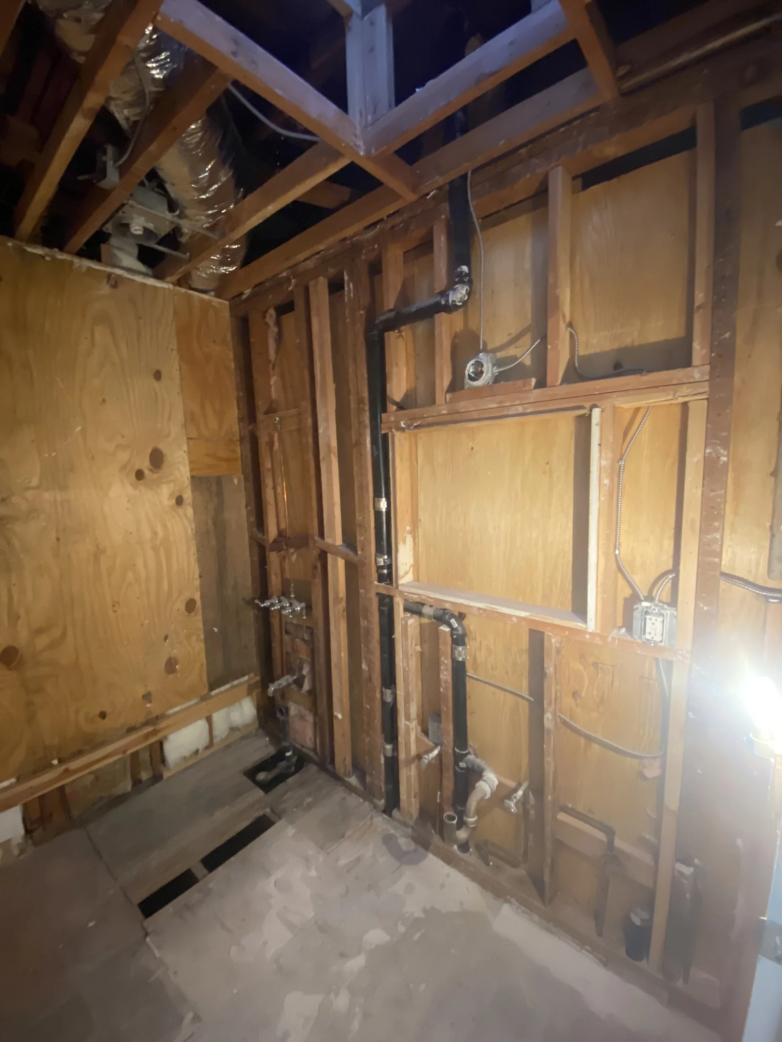New plumbing rough-in for a tub and shower valve, framed against plywood