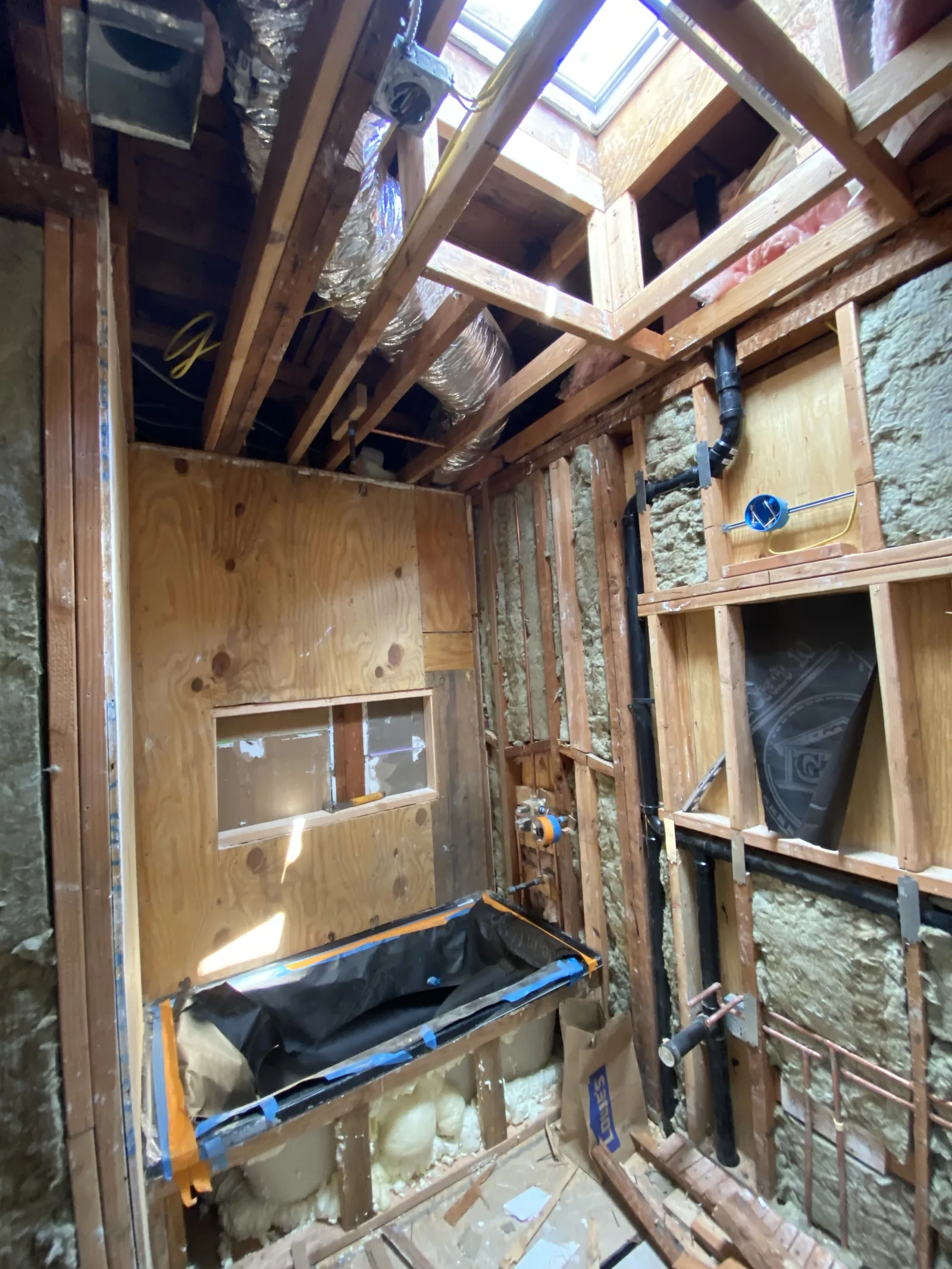 A bathroom framed with a new skylight above and waterproofing membrane over the tub