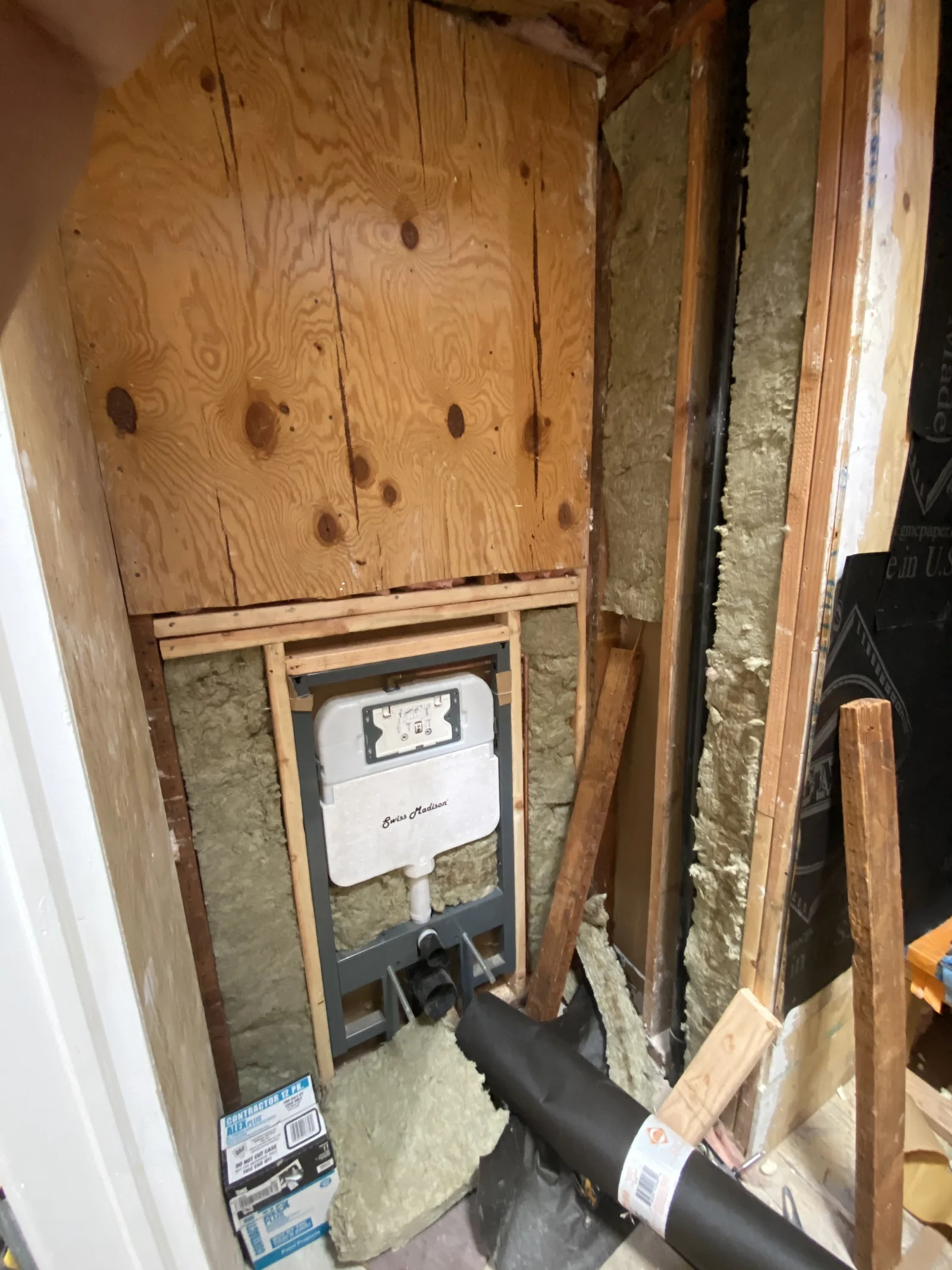 A concealed tank and carrier for a wall-mounted toilet built into the wall framing