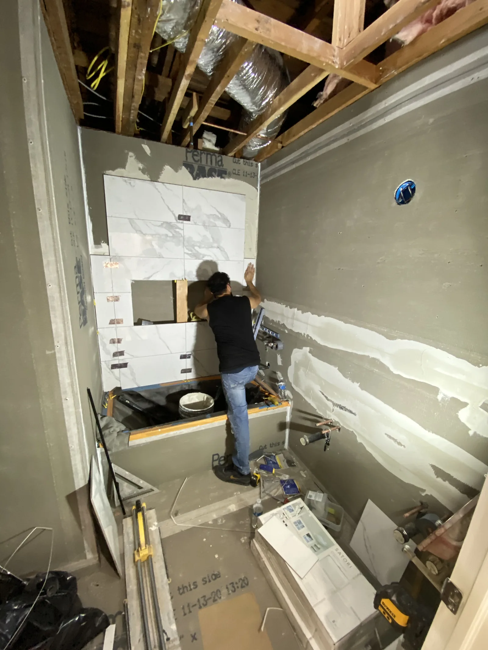 A worker setting tile around a tub